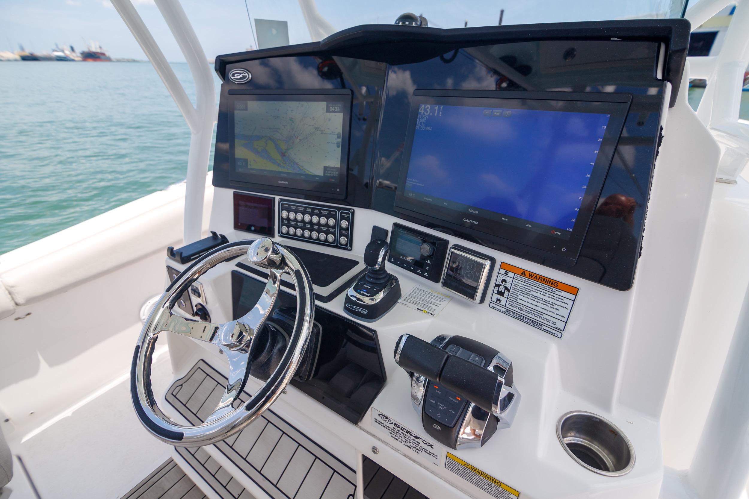 Control panel of 2021 Sea Fox 328 Commander boat with steering wheel and navigation screens.