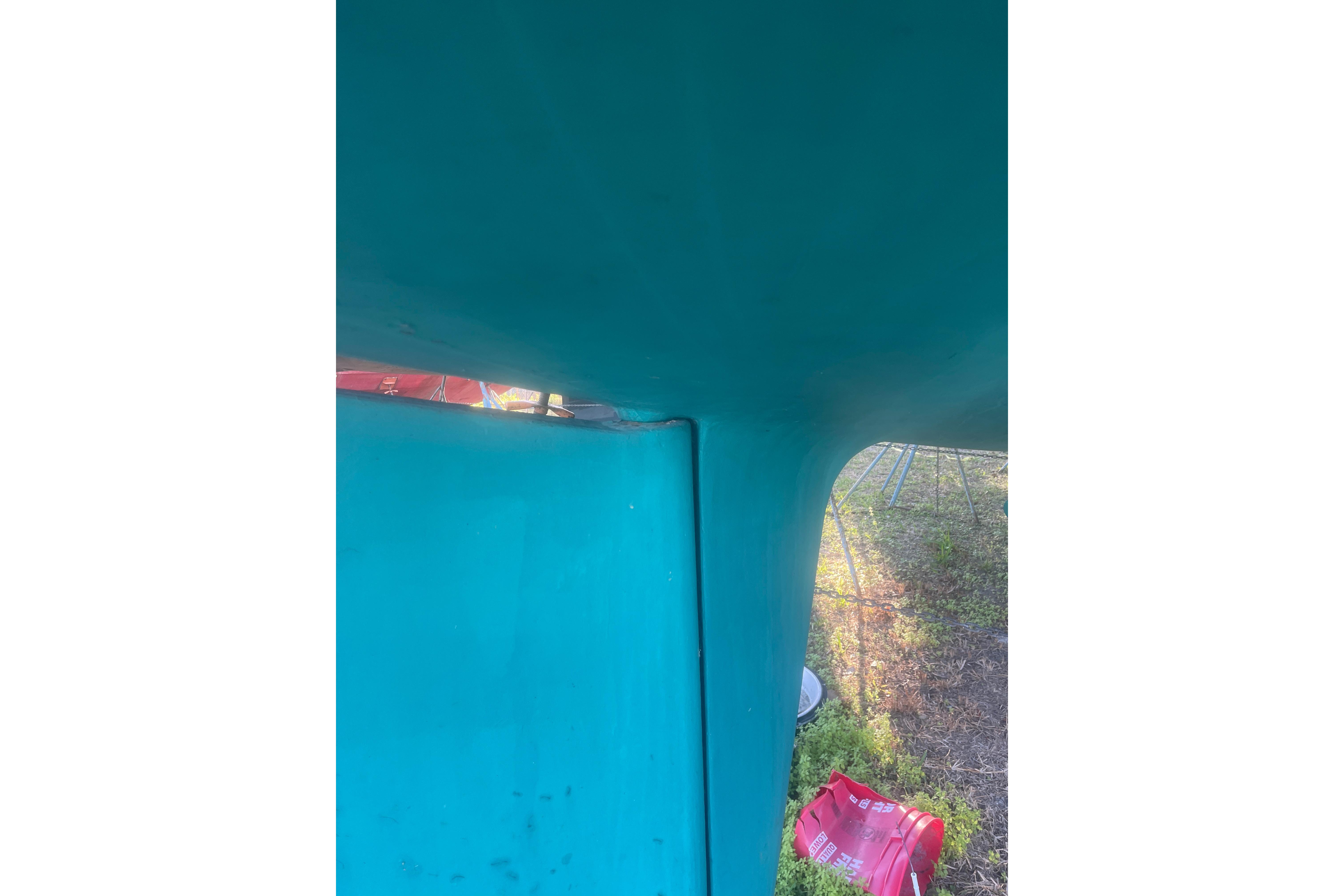 Close-up of a teal structure, possibly a boat hull, with red objects nearby.