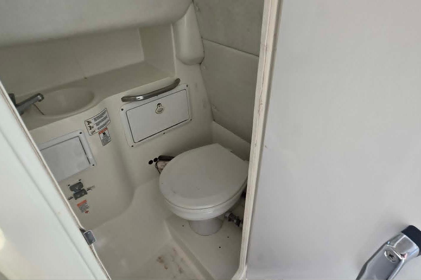 Compact marine bathroom in 2003 True World Marine 286 boat, featuring toilet and sink.