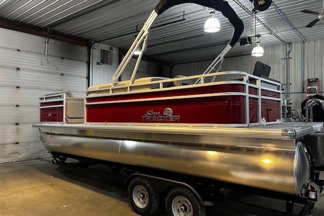 2026 Sun Tracker SportFish 22 DLX pontoon boat in a garage setting.