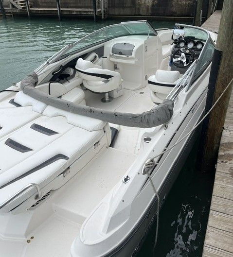 A white 2009 Monterey 234FS boat docked. It features an open cabin with seating.
