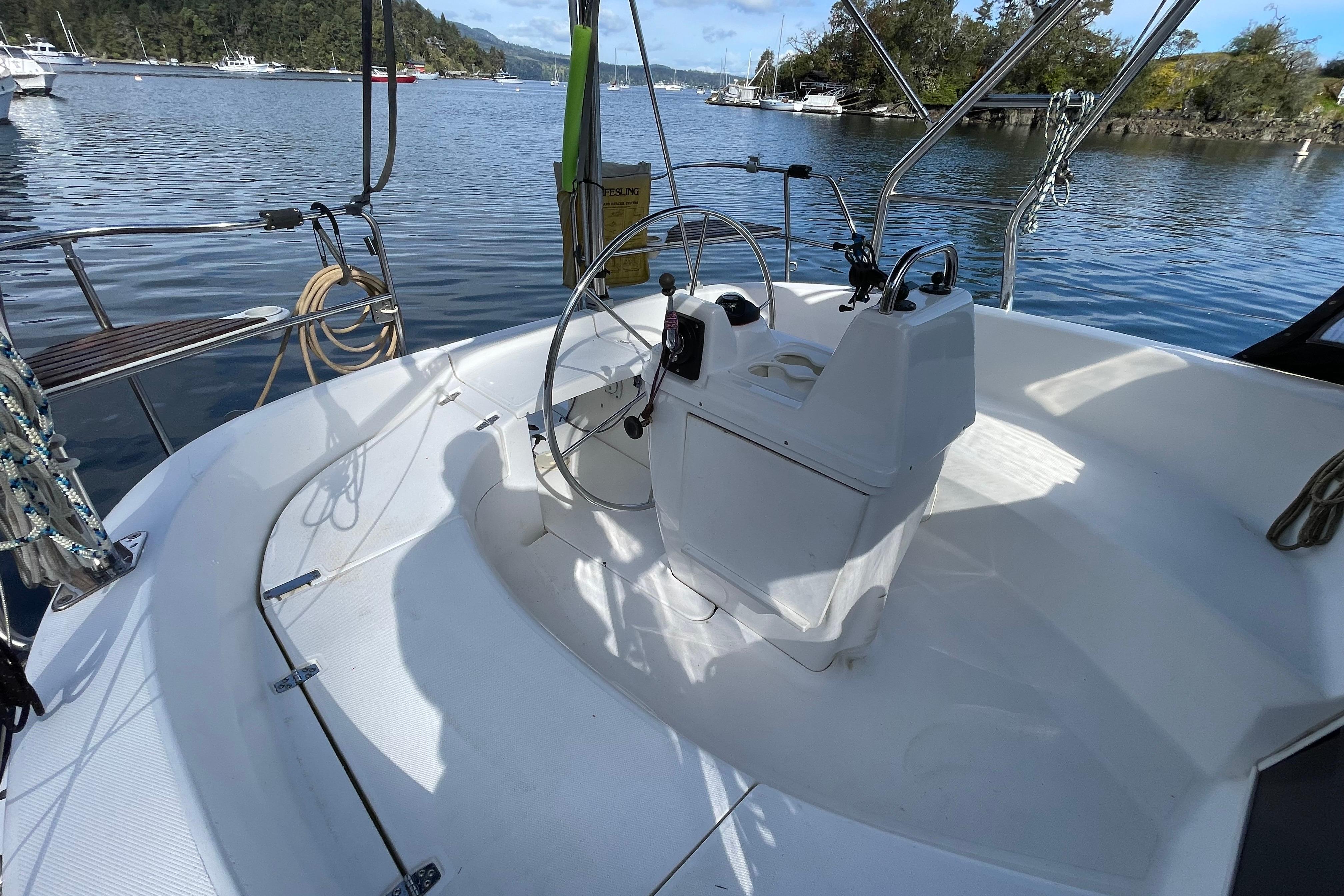 Cockpit of 2000 Hunter 340 sailboat with steering wheel, docked in scenic marina.