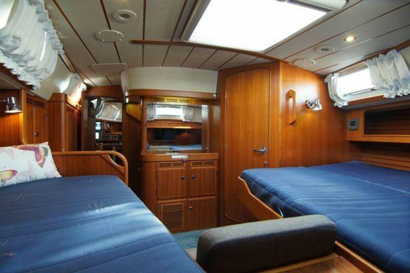 Interior of a 2002 Hallberg-Rassy 53 yacht with wooden furnishings and blue bedding.
