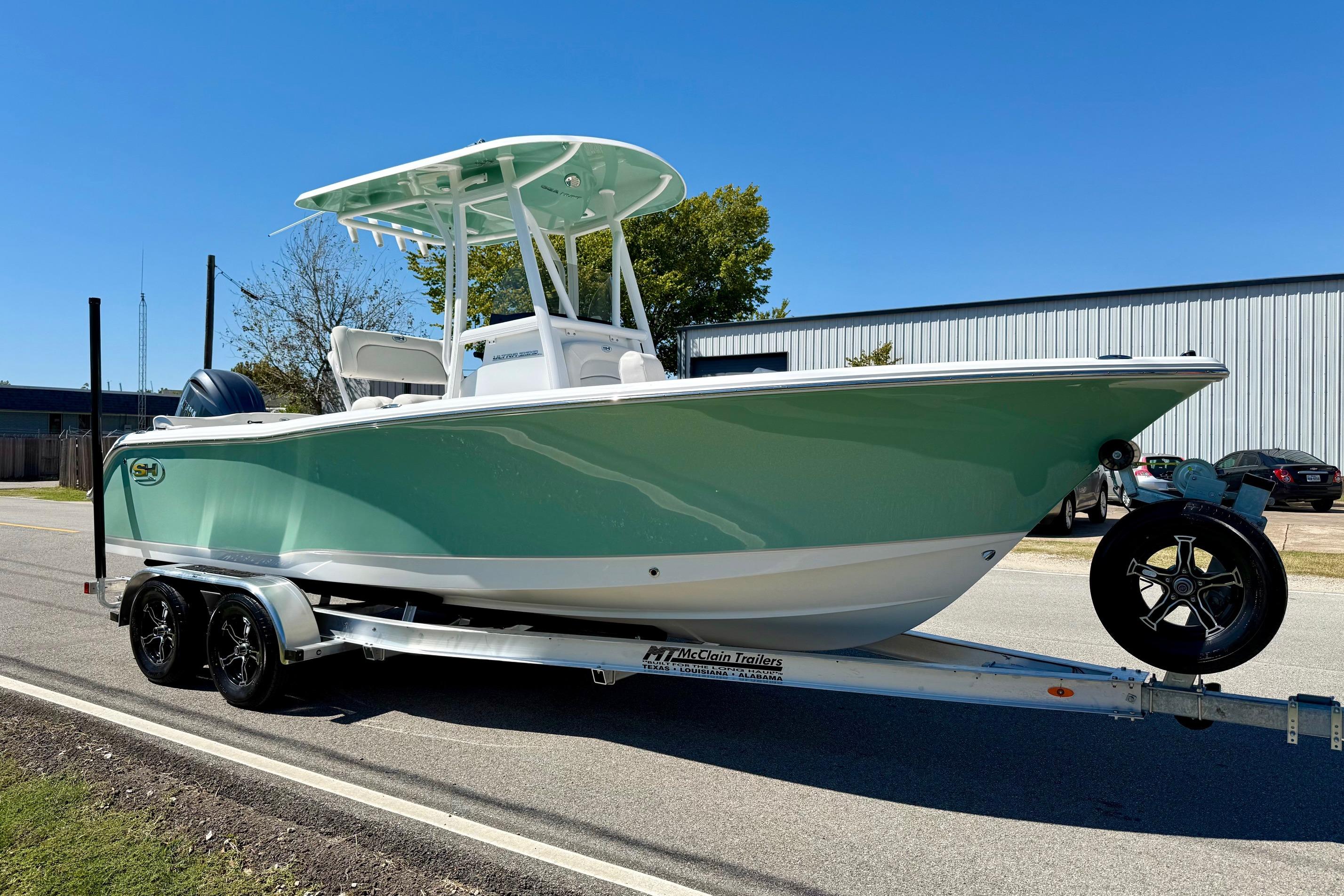 2026 Sea Hunt Ultra 229 boat on trailer, parked outdoors under clear blue sky.