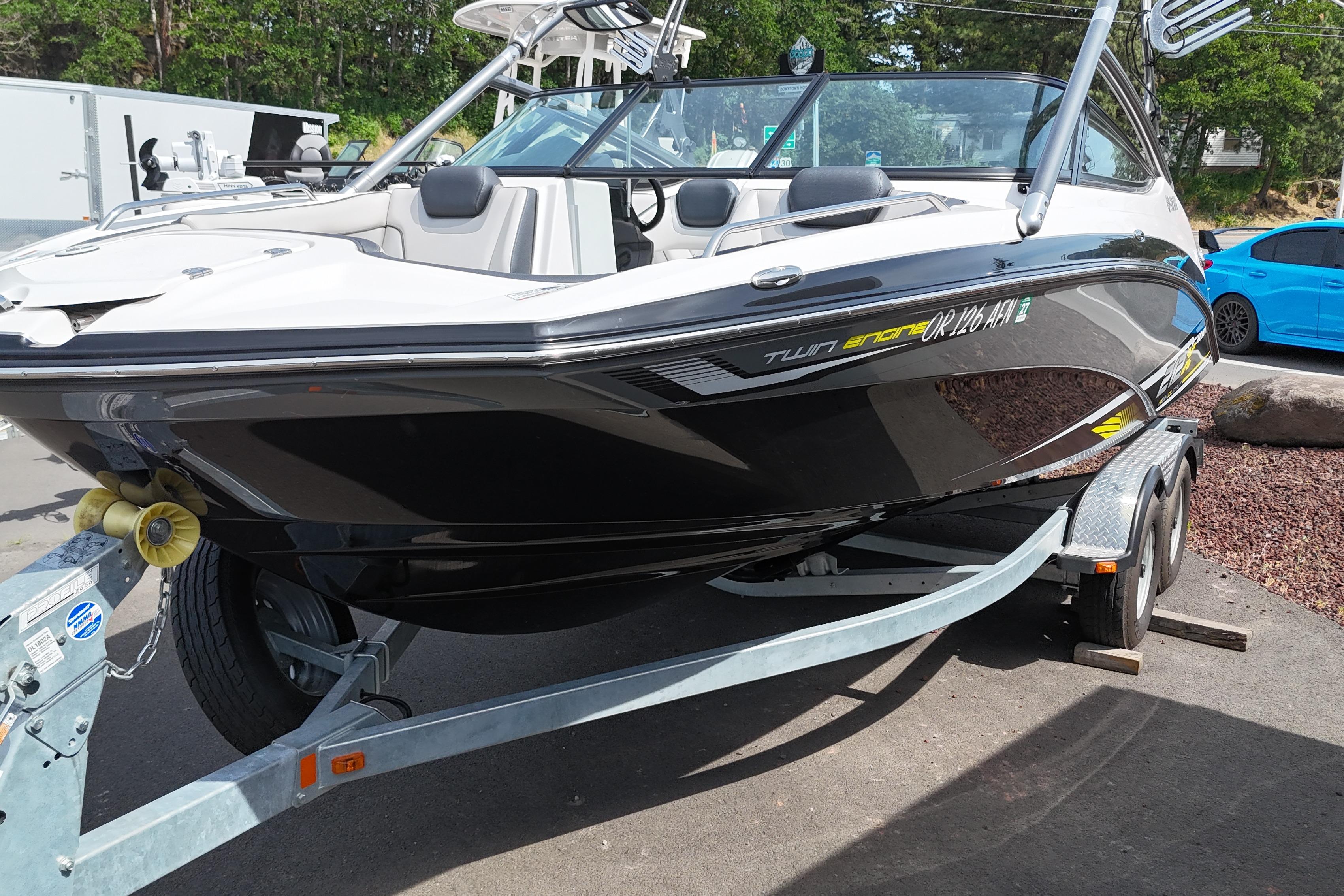 2016 Yamaha Boats 212X on trailer, sleek black and white design, parked outdoors.