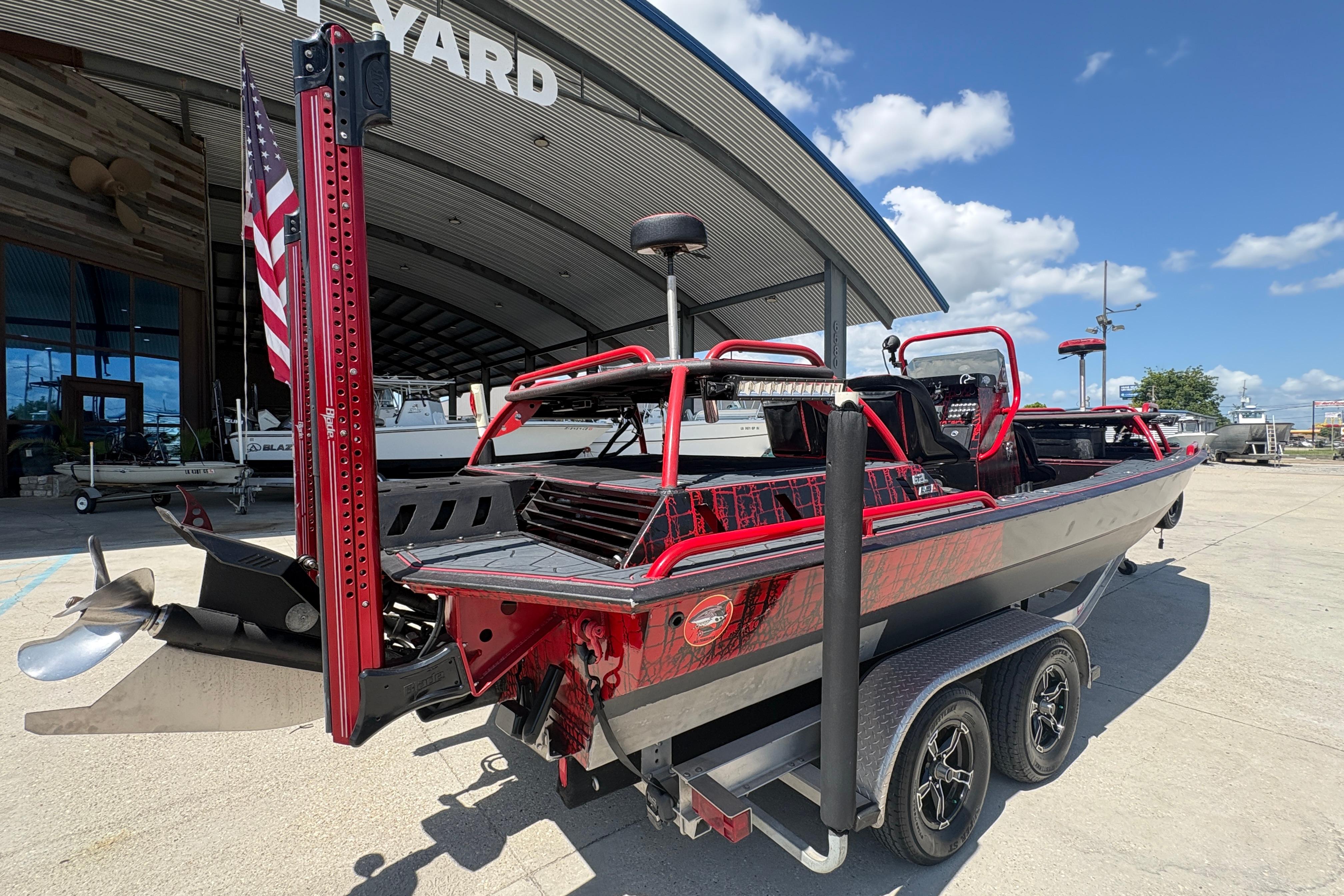 Custom 2018 Swamp Shark 24' boat on trailer, parked outside a boatyard under a clear sky.
