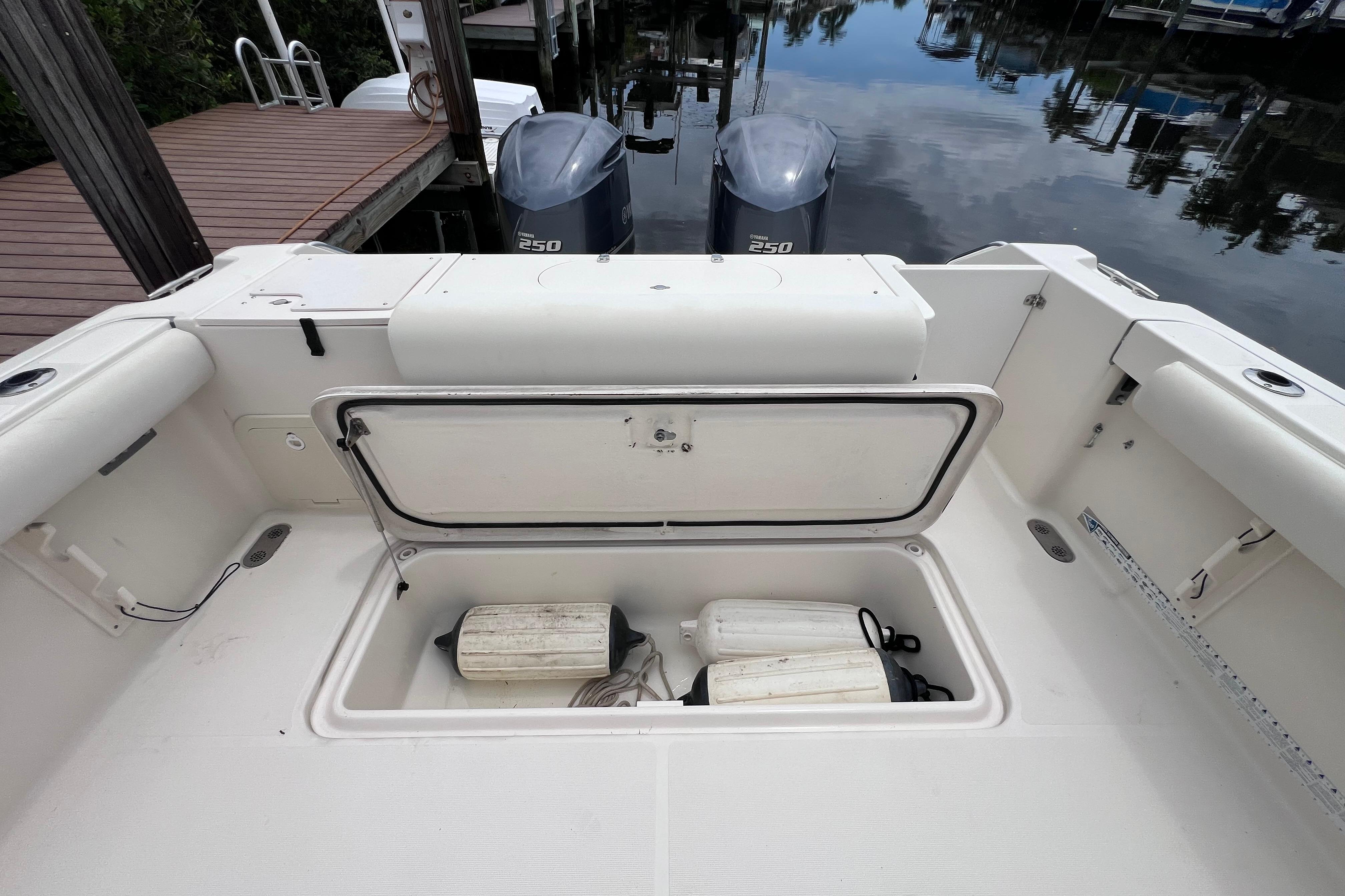 2005 Pursuit 3070 Offshore boat with open storage compartment and twin outboard motors.