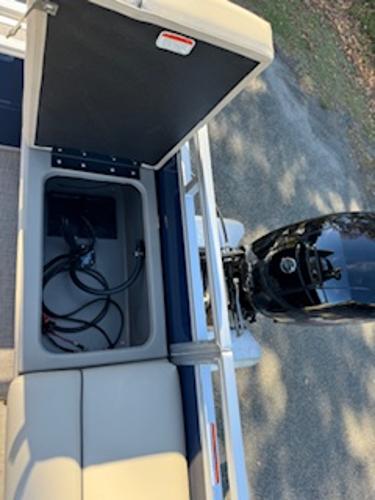 2025 Sun Tracker Fishin' Barge 22 DLX with open storage compartment and motor.