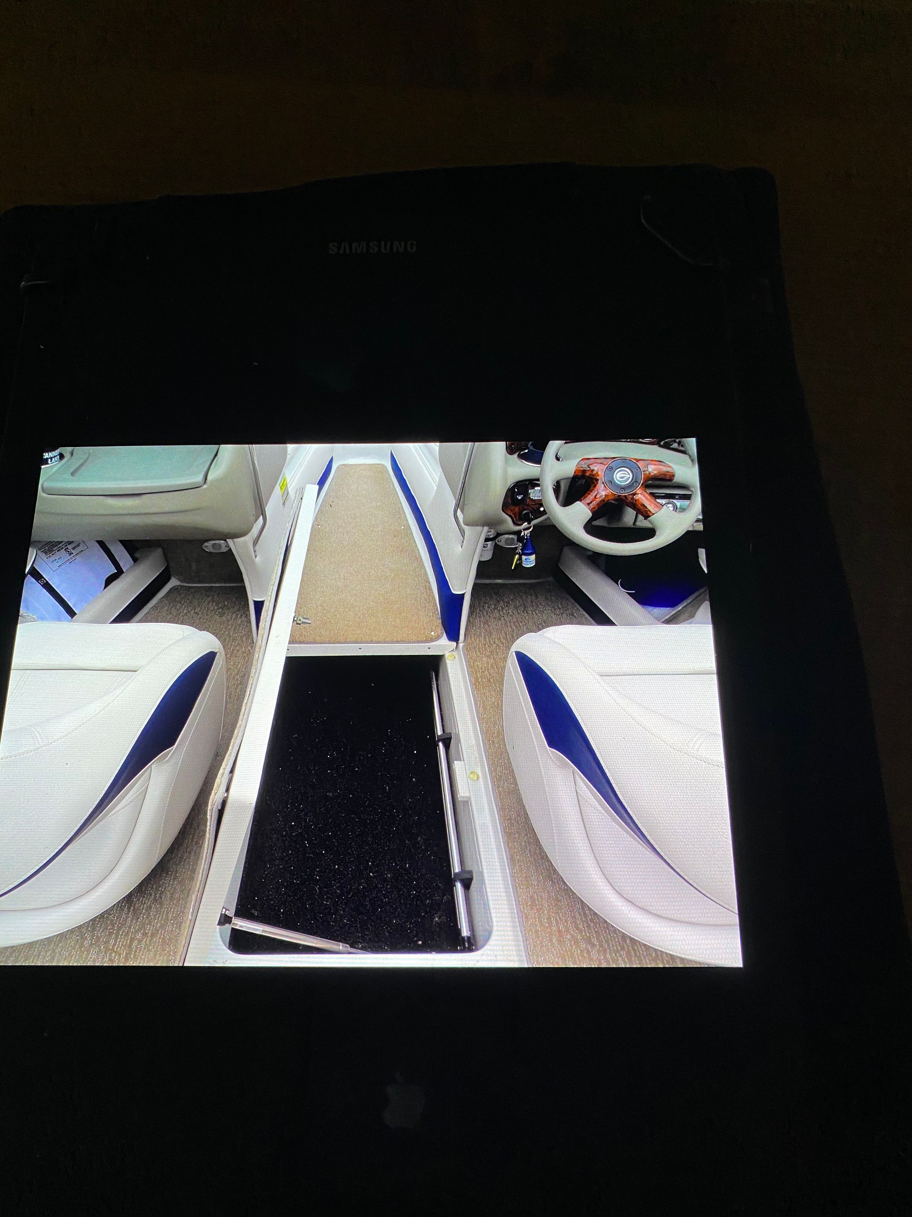 Interior view of a Crownline 21 bow rider with white and blue seats and a steering wheel.