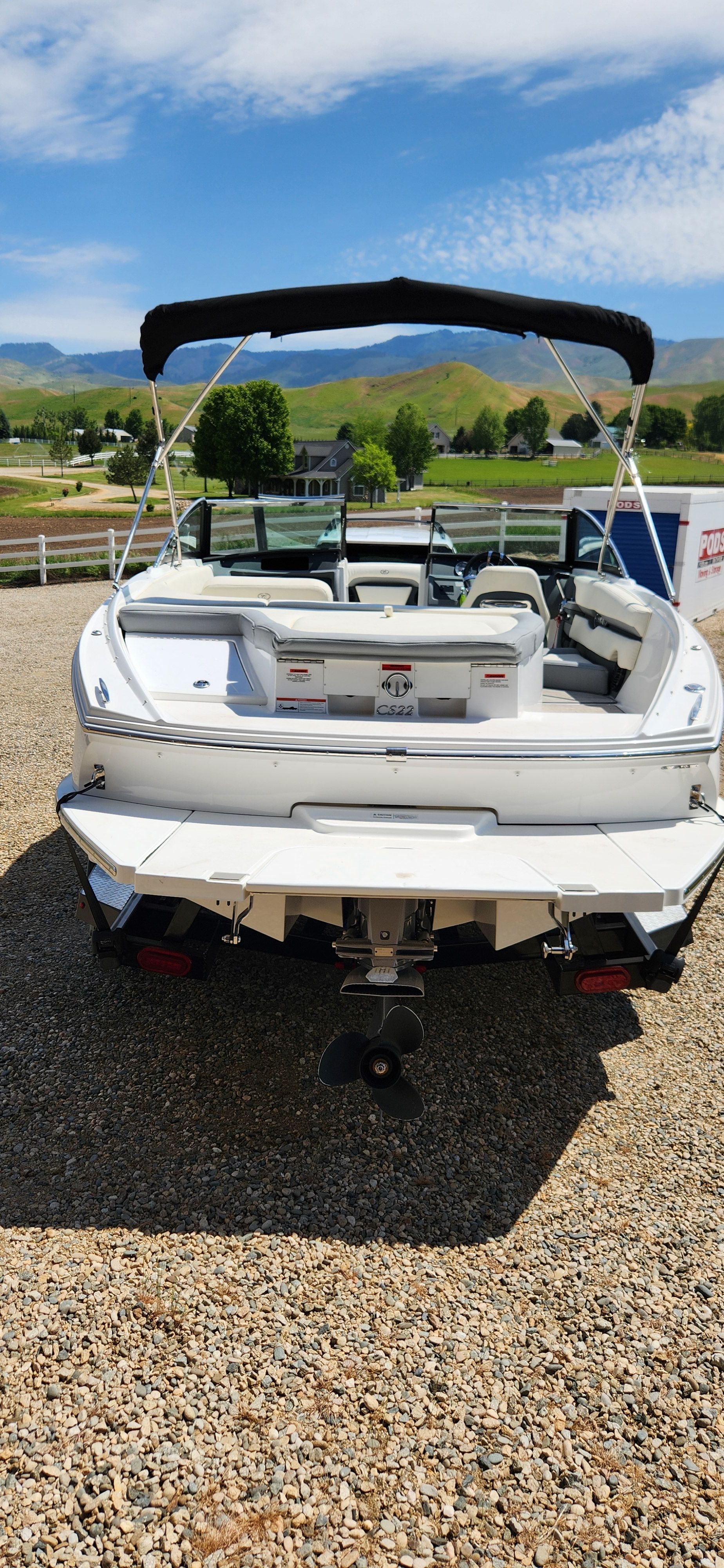 A white Cobalt CS22 boat is on a gravel path with green landscape in the background.