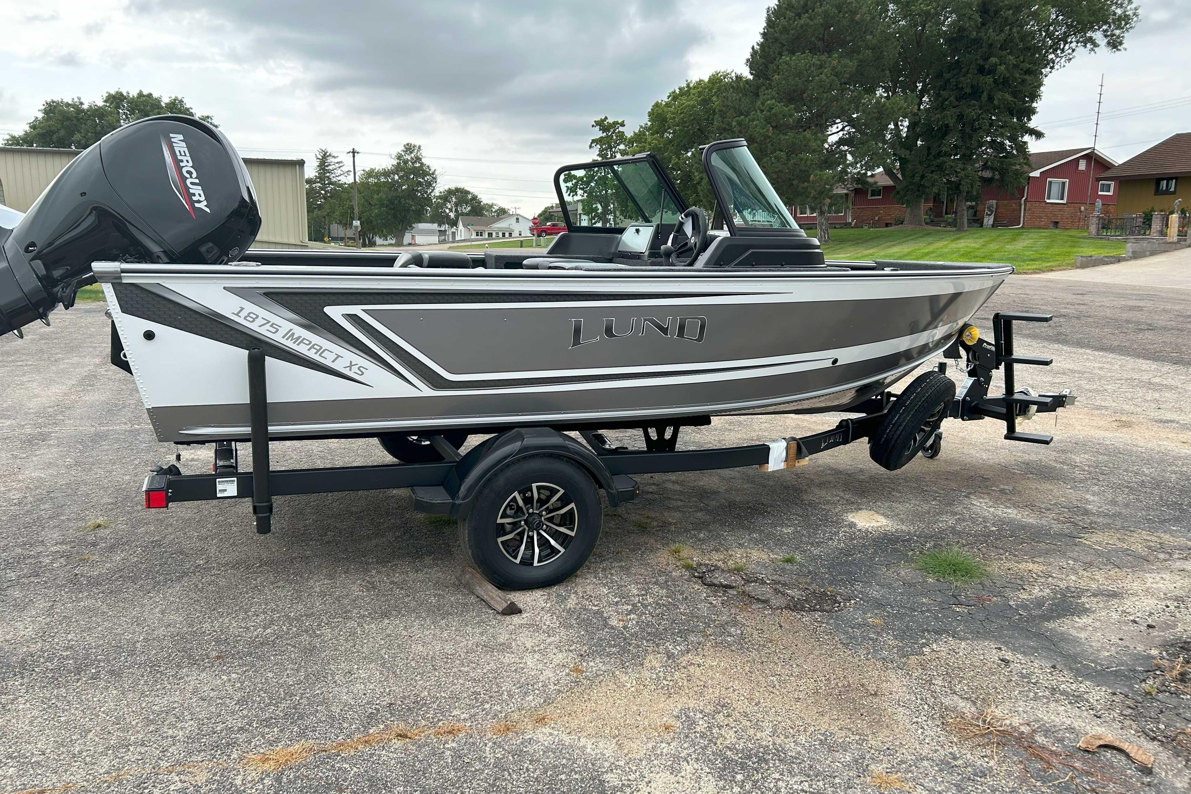 2026 Lund 1875 Impact XS Sport boat on trailer, parked outdoors.