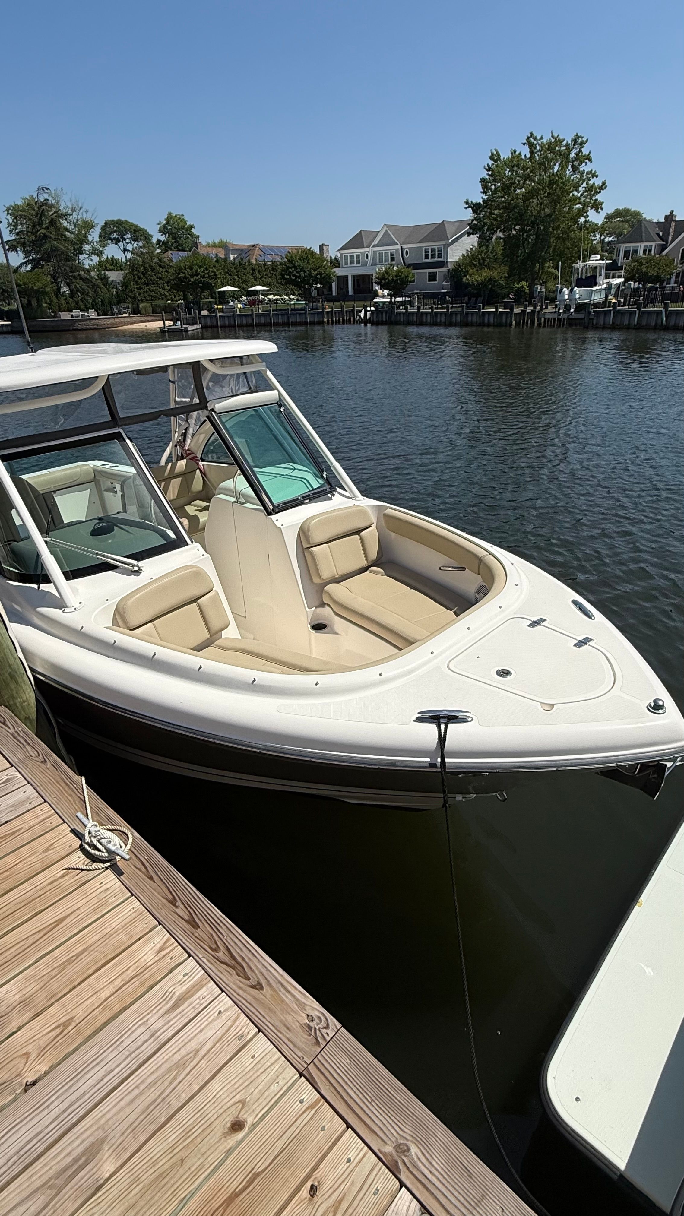 A 2016 Pursuit DC 265 Dual Console boat docked at a wooden pier in calm water.