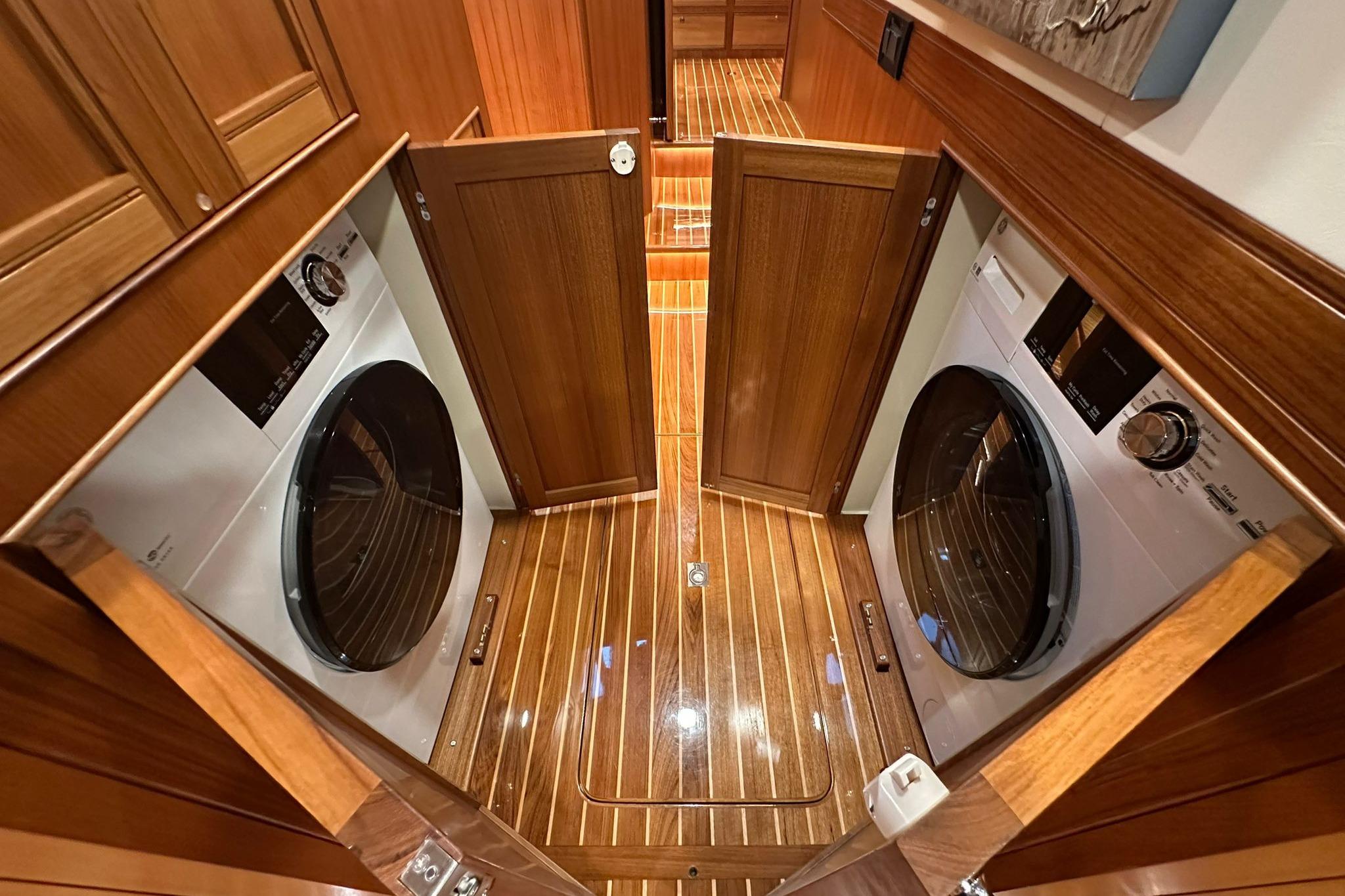 Laundry area with dual washers in 2023 Marlow Explorer 66E-CB yacht, featuring wooden cabinetry.