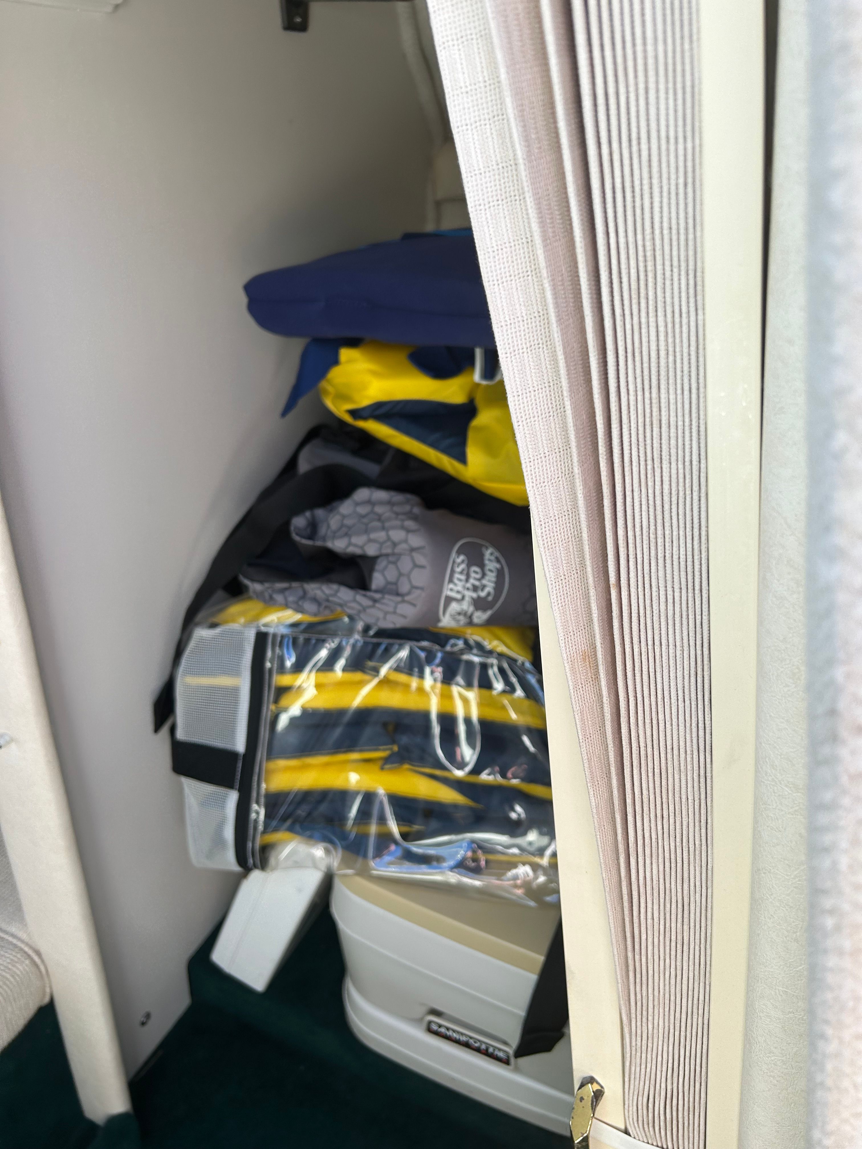 A compact storage area with life jackets and a portable toilet.