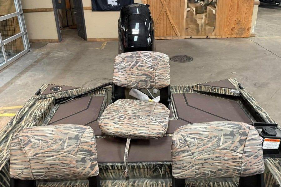2026 Tracker Grizzly 1754 SC All-Welded boat with camo seats in a showroom.