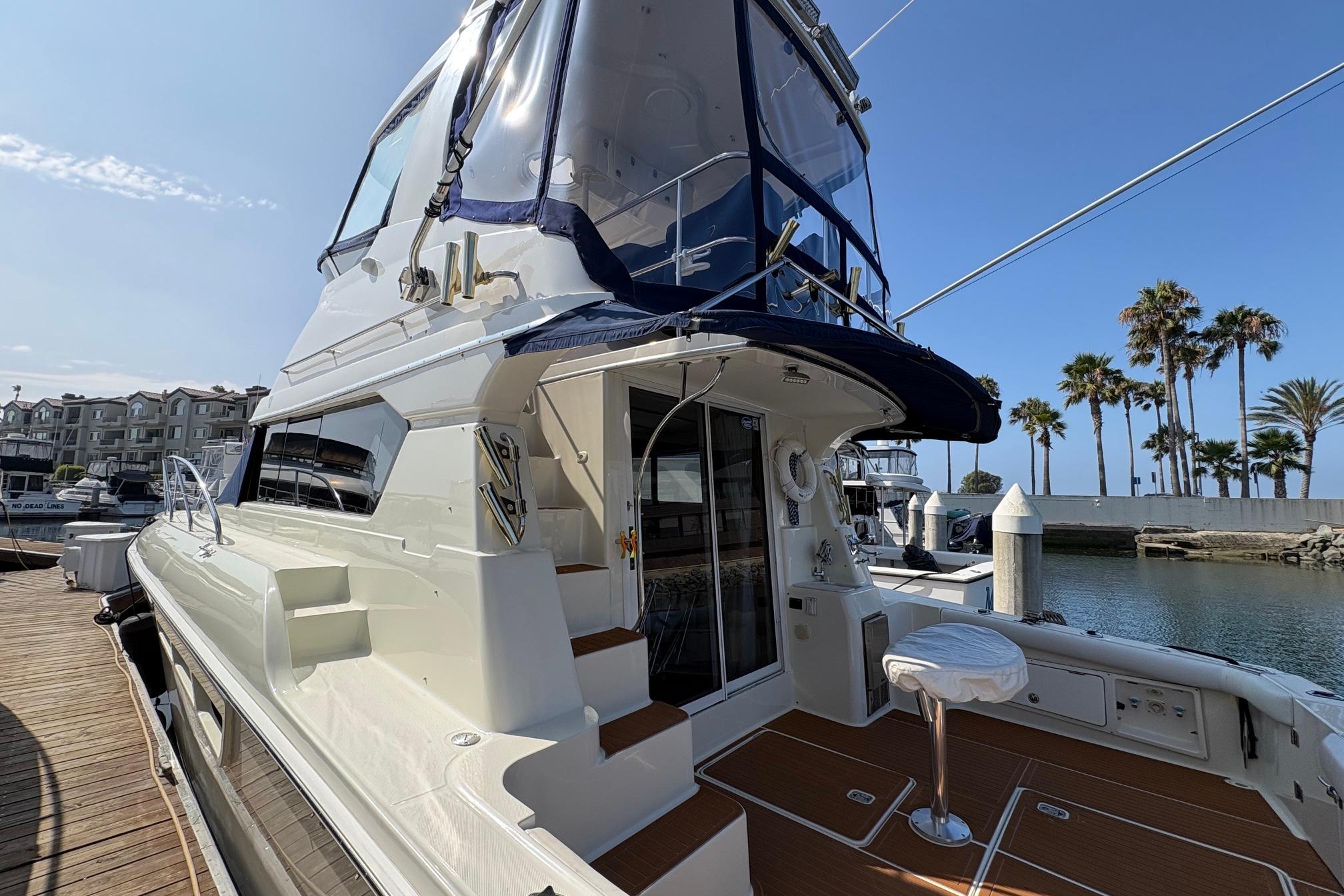 2000 Silverton 42 Convertible yacht docked at marina with palm trees in background.