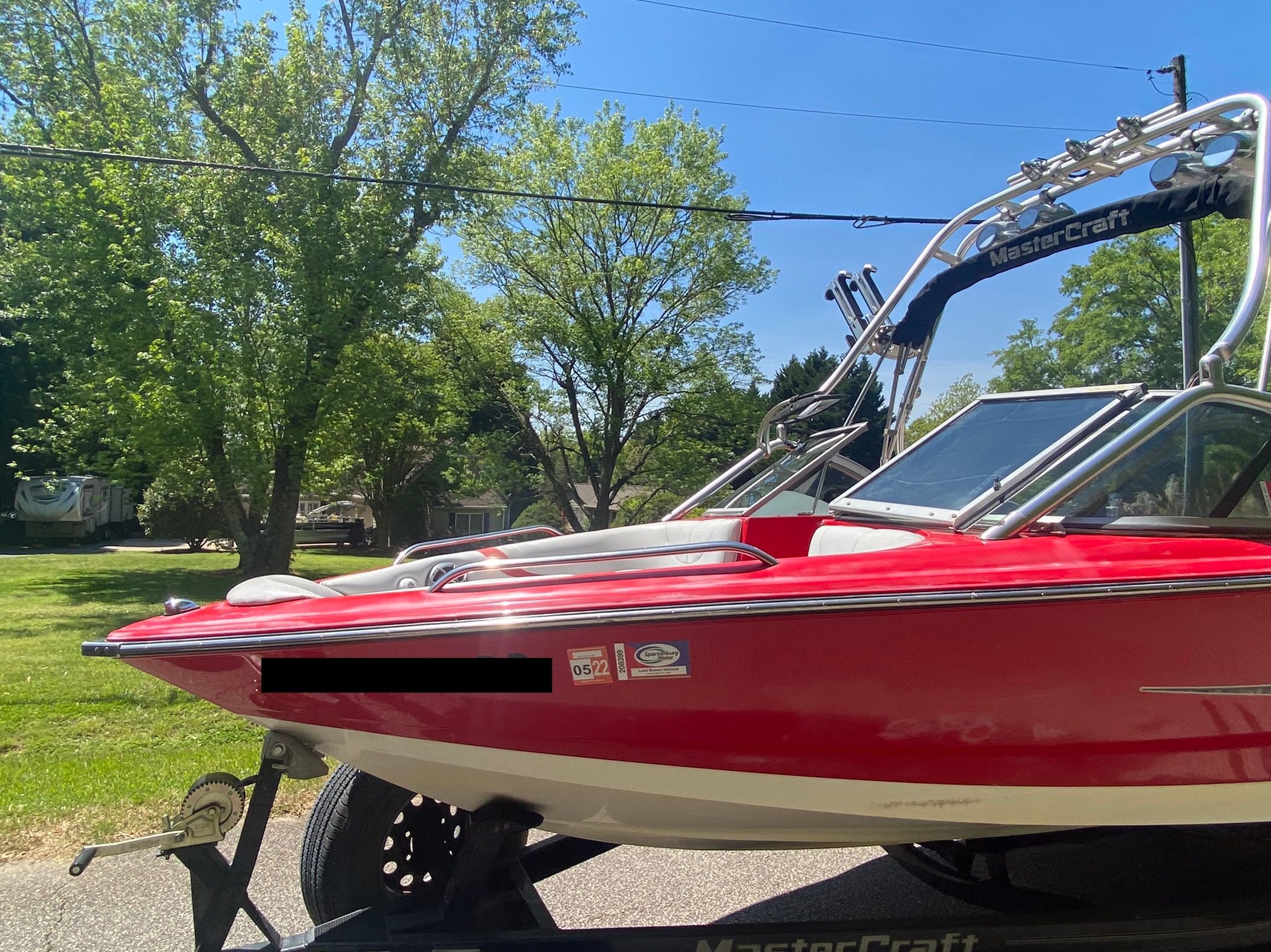 A red 2004 MasterCraft X-9 boat on a trailer in a green setting.