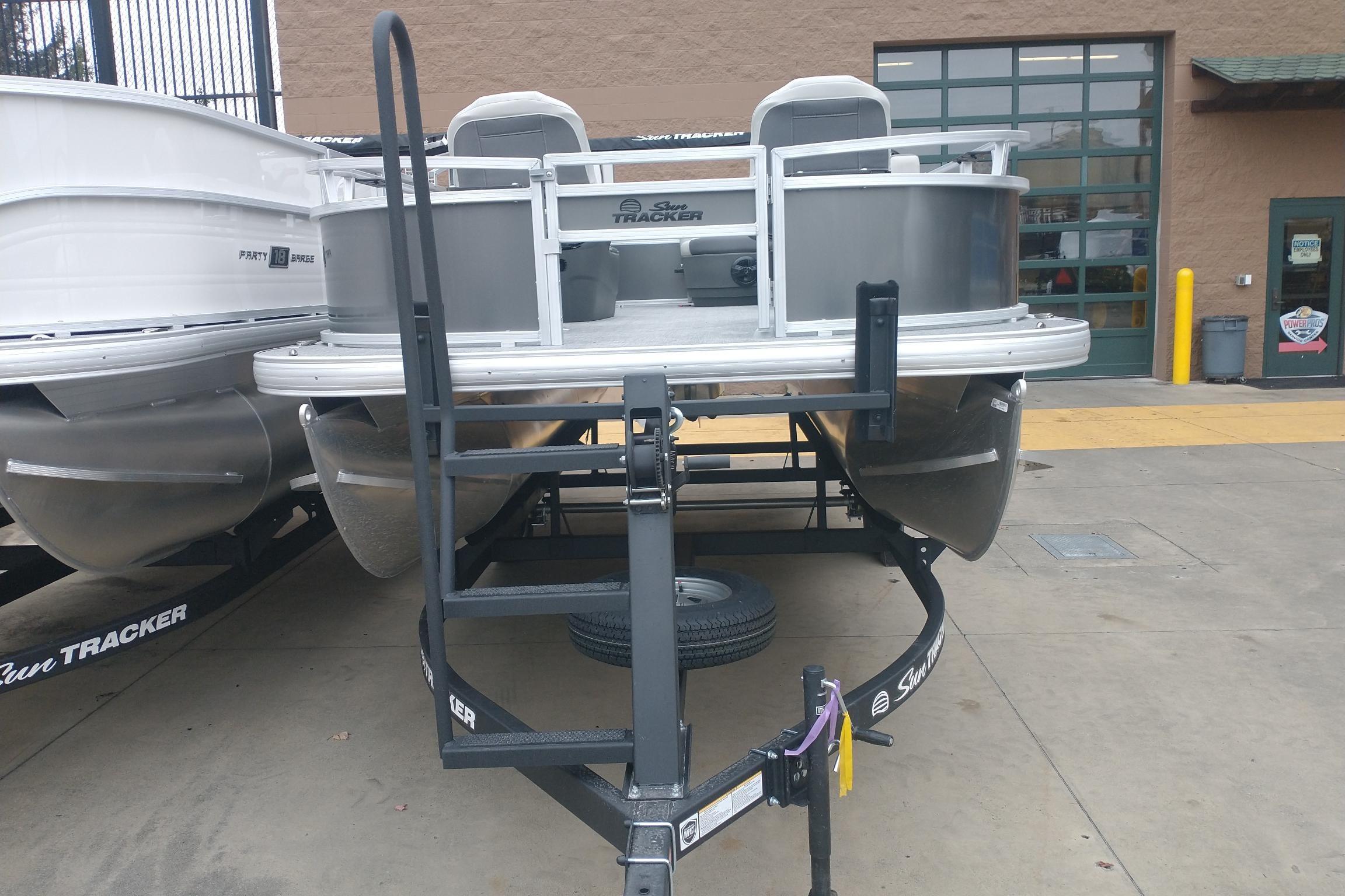 2026 Sun Tracker Bass Buggy 16 XL Select pontoon boat on trailer at dealership.