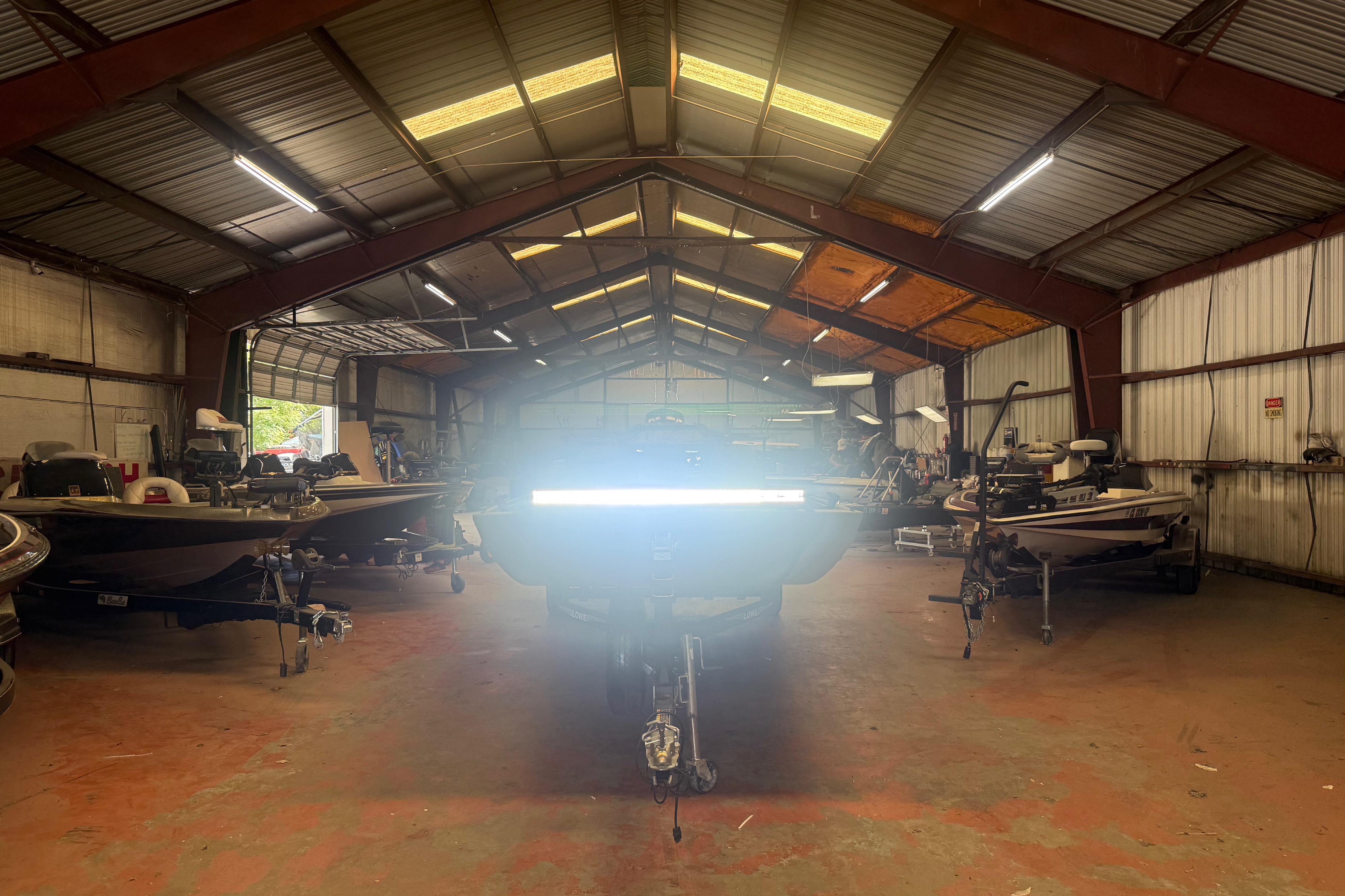 2020 Lowe Roughneck 2070 Big River boat in a spacious warehouse with other boats.