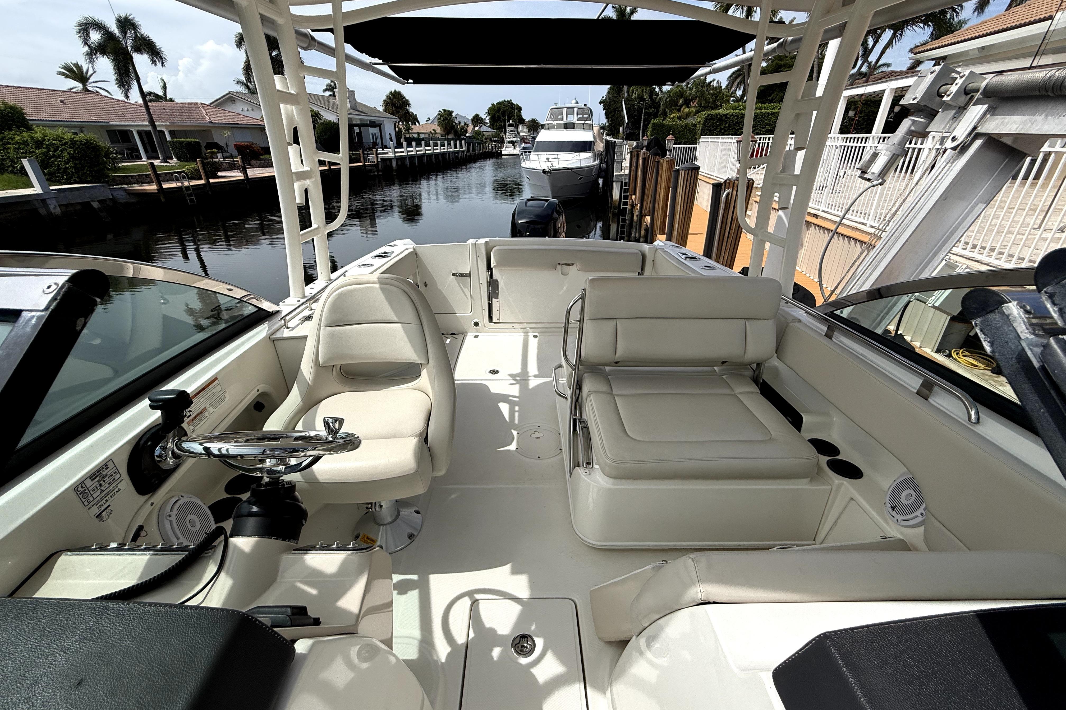 2018 Boston Whaler 230 Vantage boat interior with seating and steering wheel, docked by a canal.