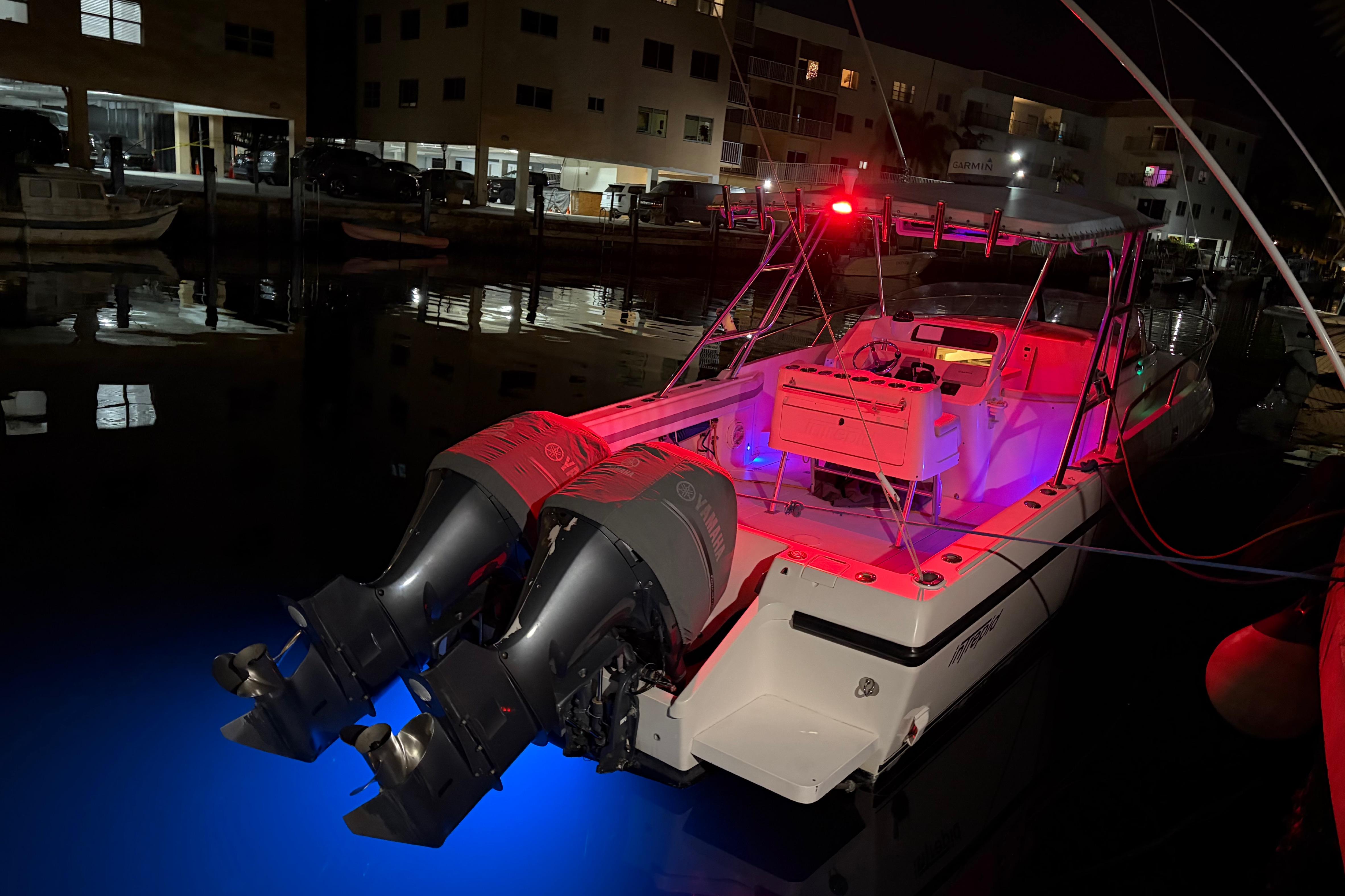1998 Intrepid 339 Walkaround boat with illuminated deck and dual outboard motors at night.