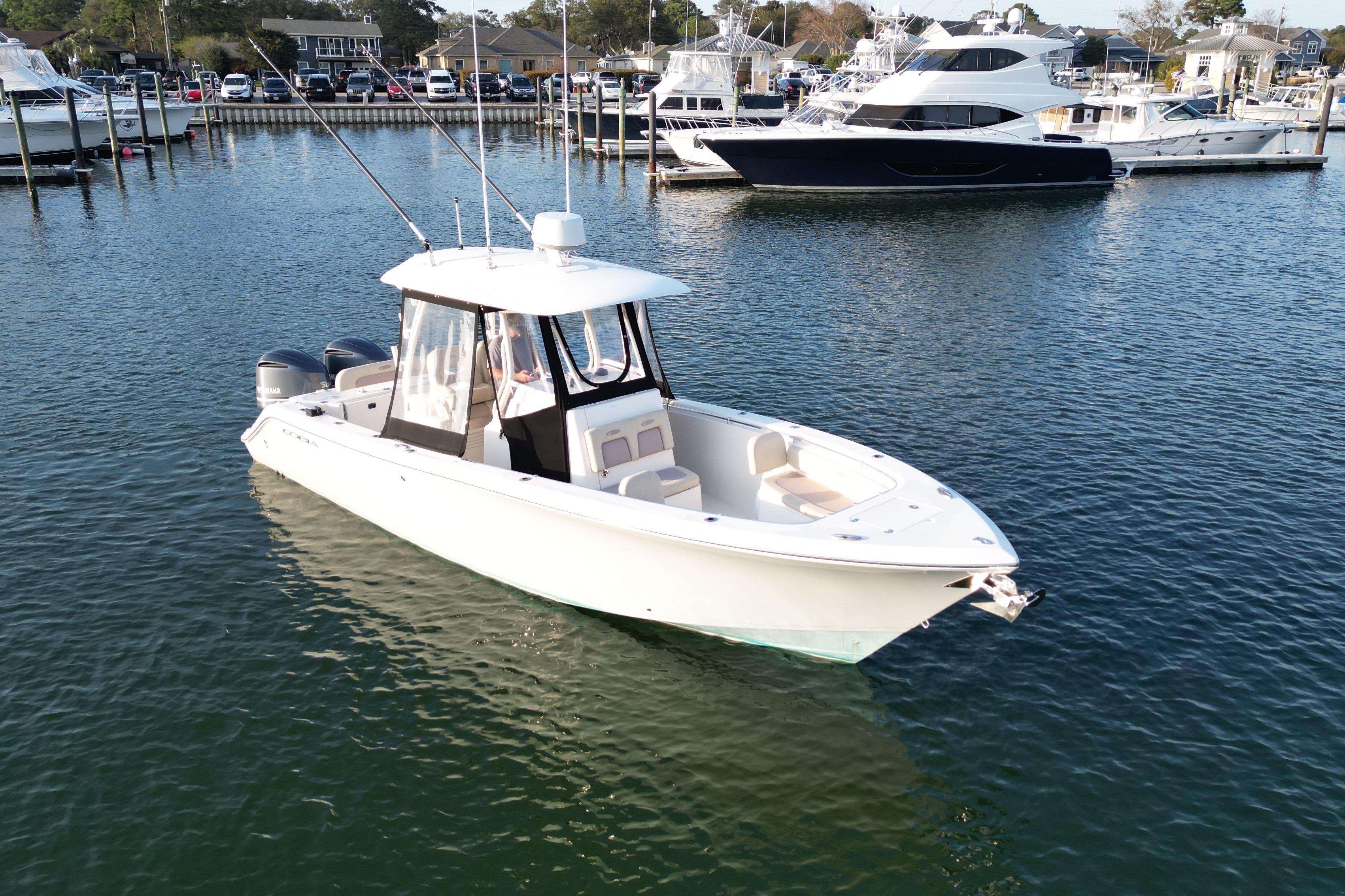 2016 Cobia 296 Center Console boat docked in a marina, surrounded by other vessels.