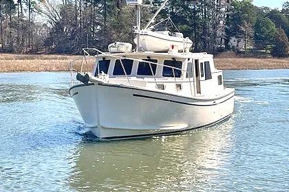 1997 Rosborough Trawler cruising on a calm river with trees in the background.