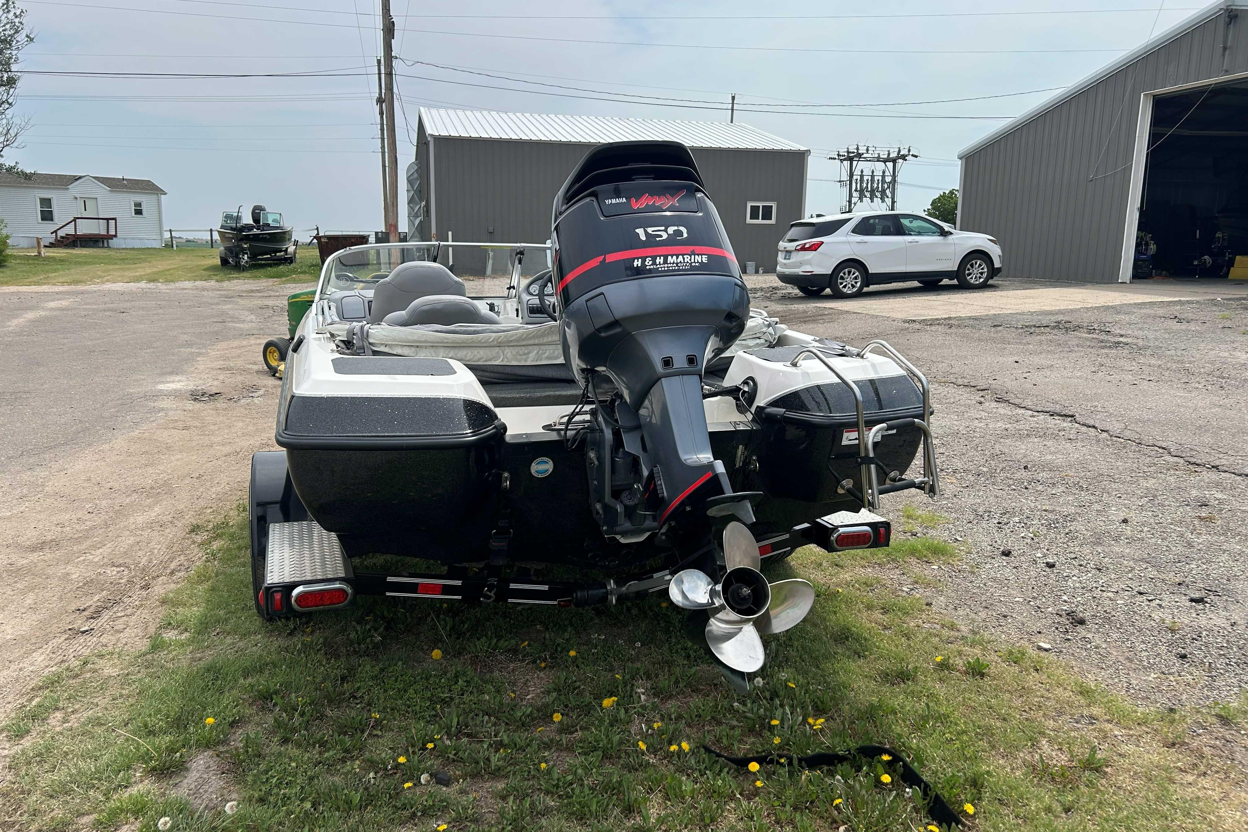 2010 Skeeter SL 180 boat with outboard motor, parked outdoors near a garage.