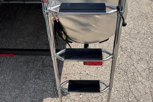 Ladder on 2026 Sun Tracker SportFish 20 DLX boat, resting on pavement.