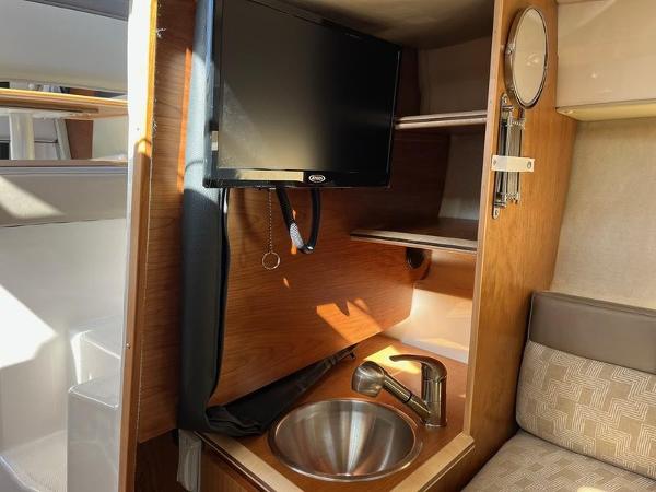 2025 Cutwater C-248 C Coupe interior with TV, sink, and wooden cabinetry.