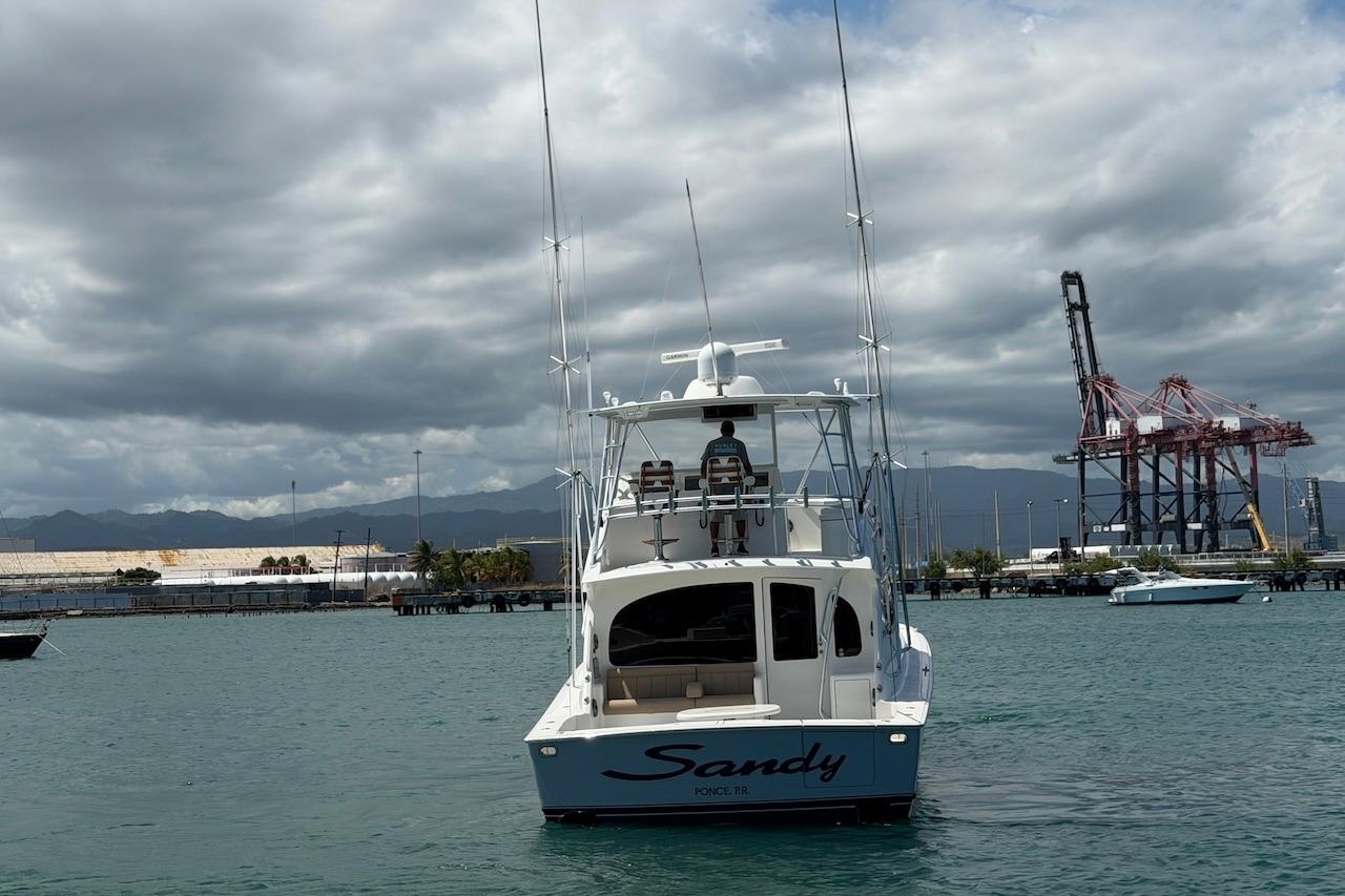 Viking 50 Convertible 2012 yacht "Sandy" in a harbor with industrial cranes.