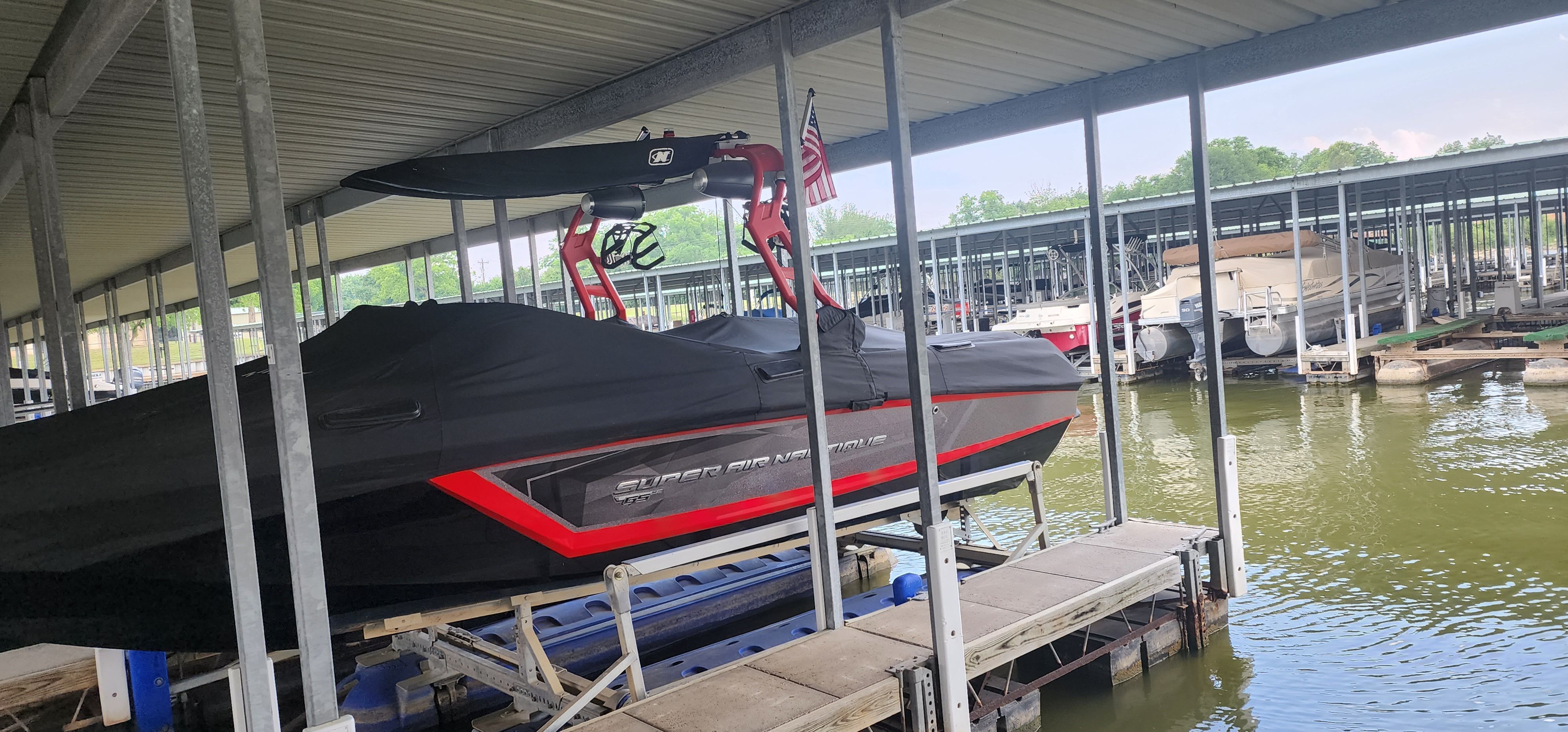 A 2019 Nautique Super Air Nautique GS22 is docked in a covered marina.