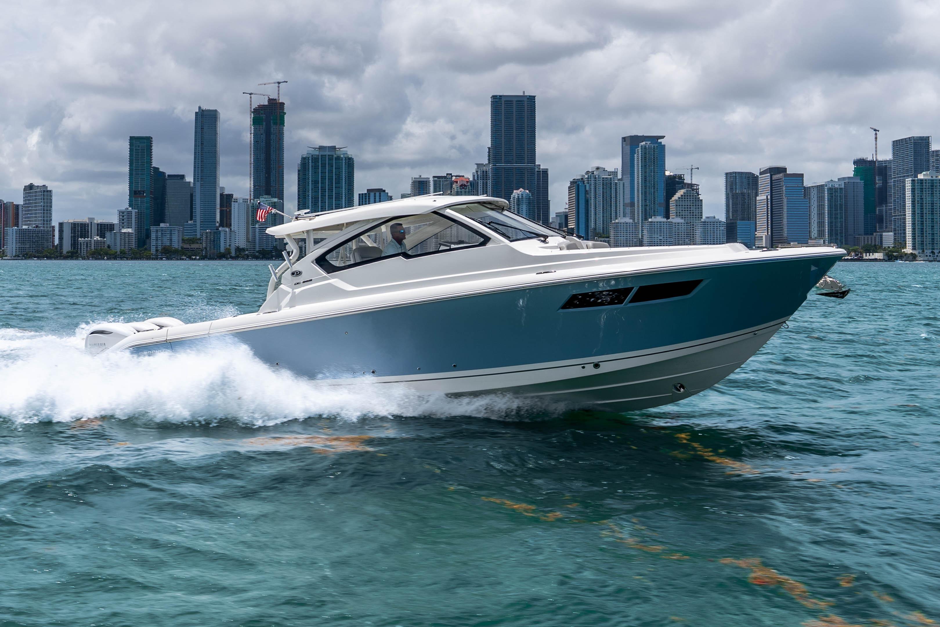 2026 Pursuit DC 365 Dual Console cruising on water with city skyline backdrop.