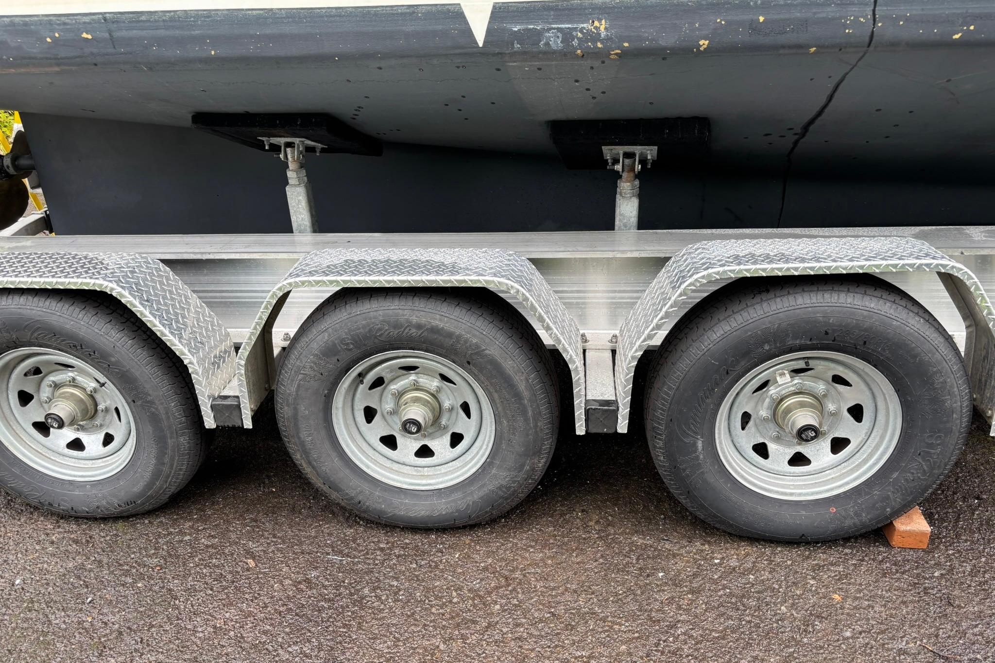 Triple-axle trailer supporting a 2020 SeaPiper 35 boat on a paved surface.