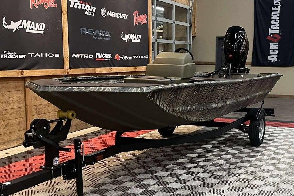2026 Tracker Grizzly 1648 SC boat on display in showroom with branded banners.