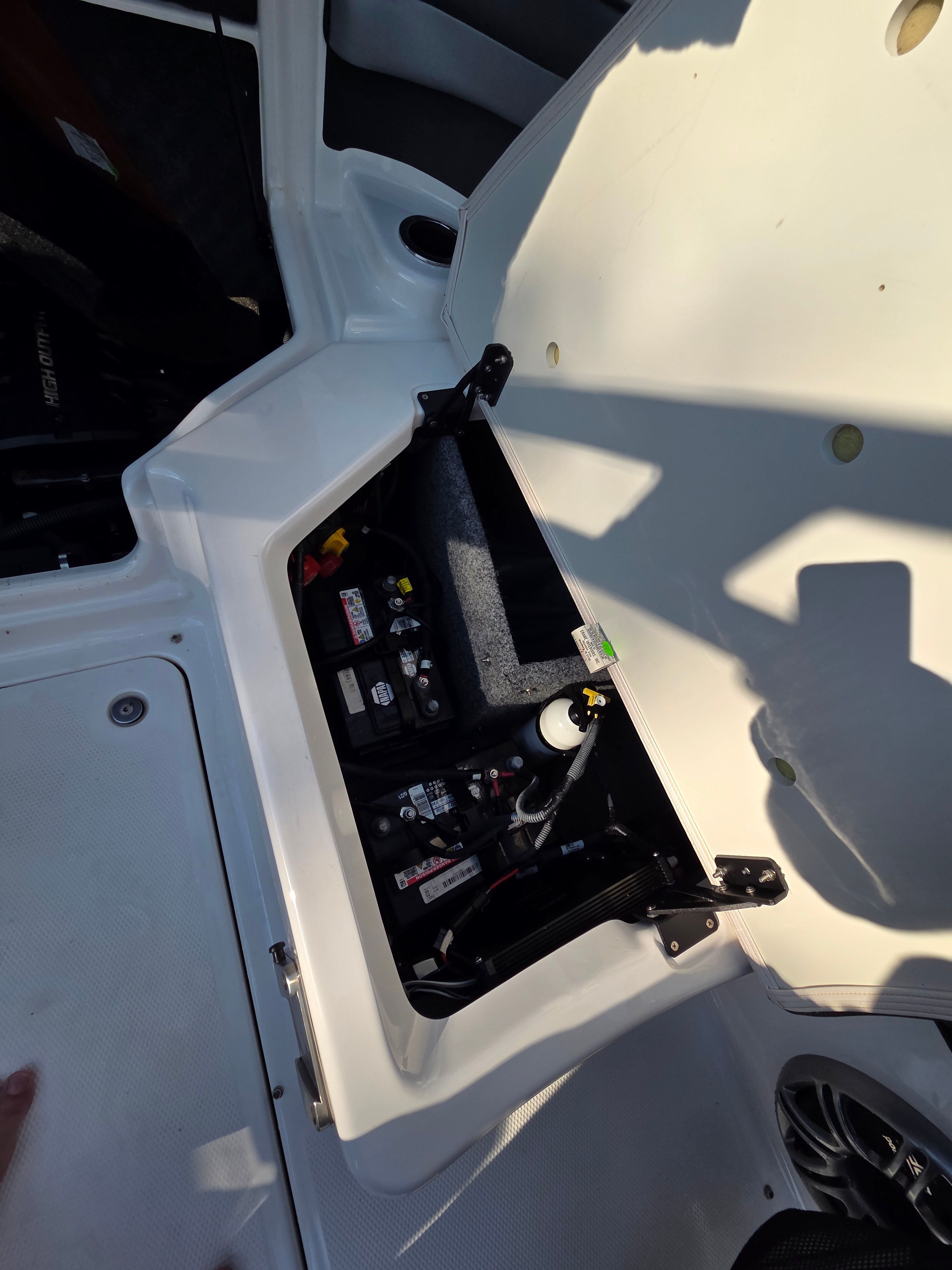 An open storage compartment on a boat reveals batteries and electronics.
