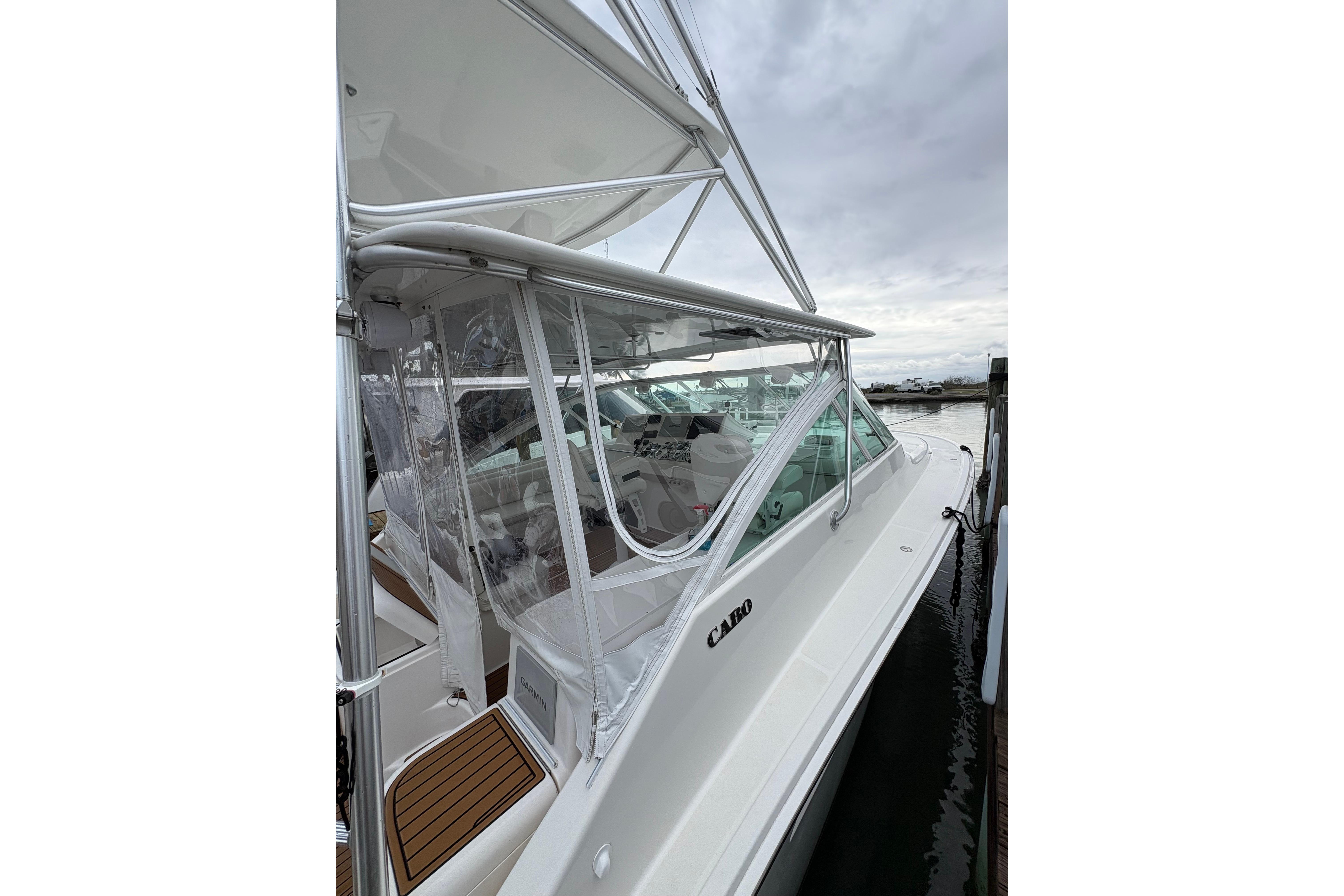 2004 Cabo 40 Hardtop Express boat docked, featuring sleek design and clear enclosure.