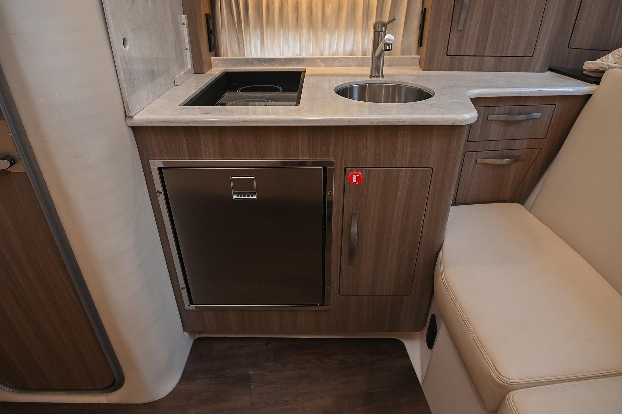 2021 Regal 33 Express yacht kitchenette with sink, stove, and compact fridge.