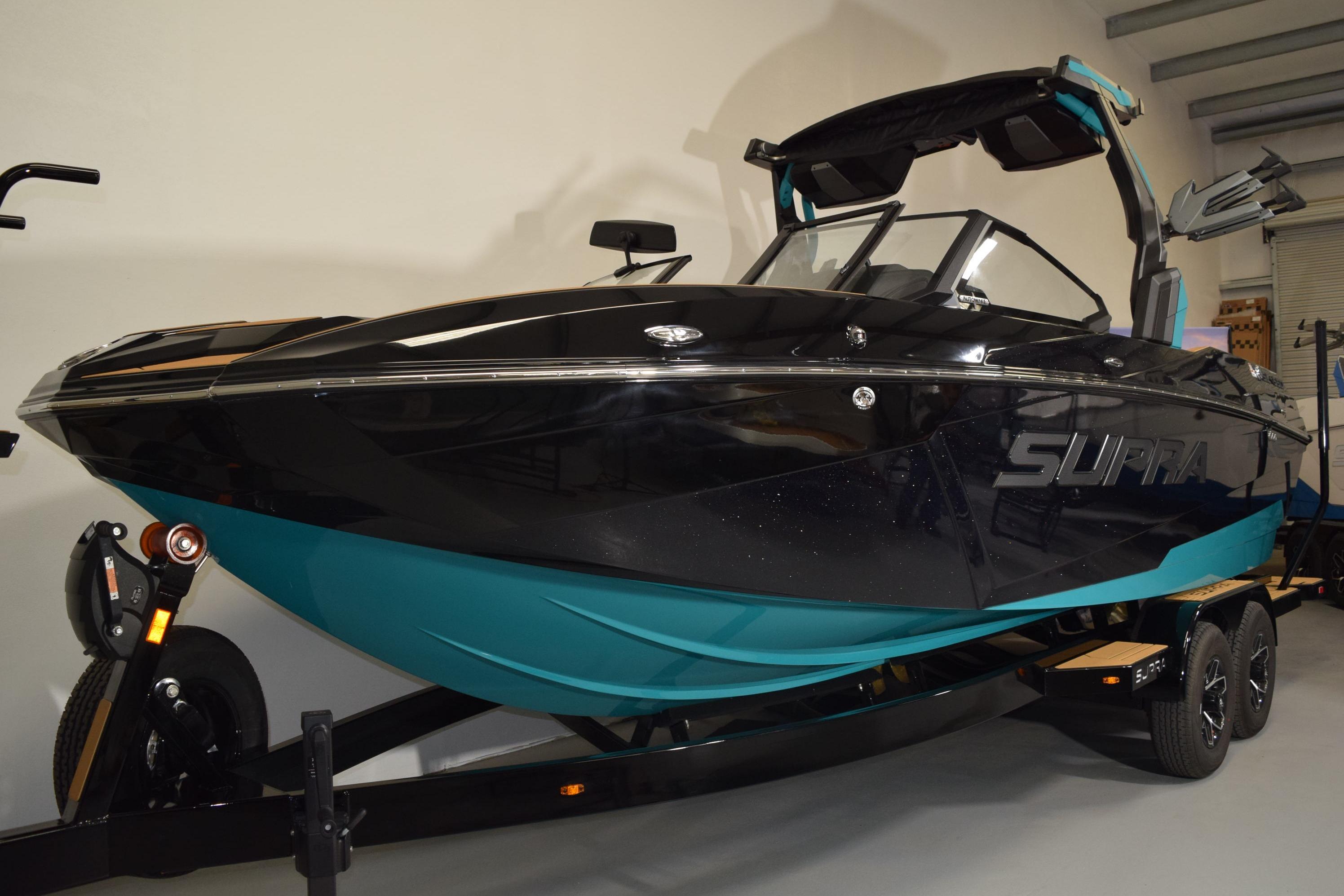 2026 Supra SL 550 boat in showroom, black and teal design on trailer.