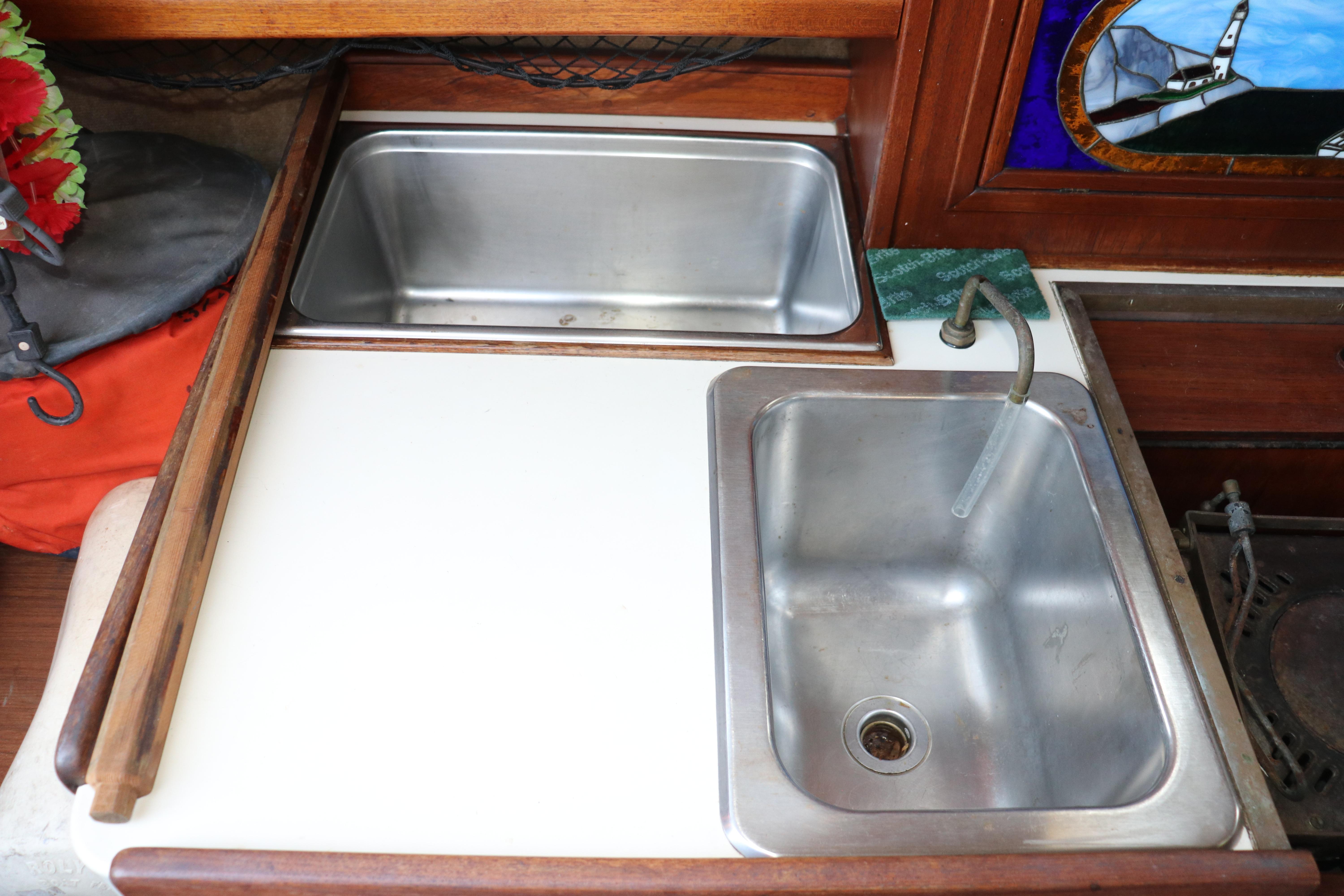1982 Pacific Seacraft Flicka 20 galley with dual stainless steel sinks and wooden cabinetry.
