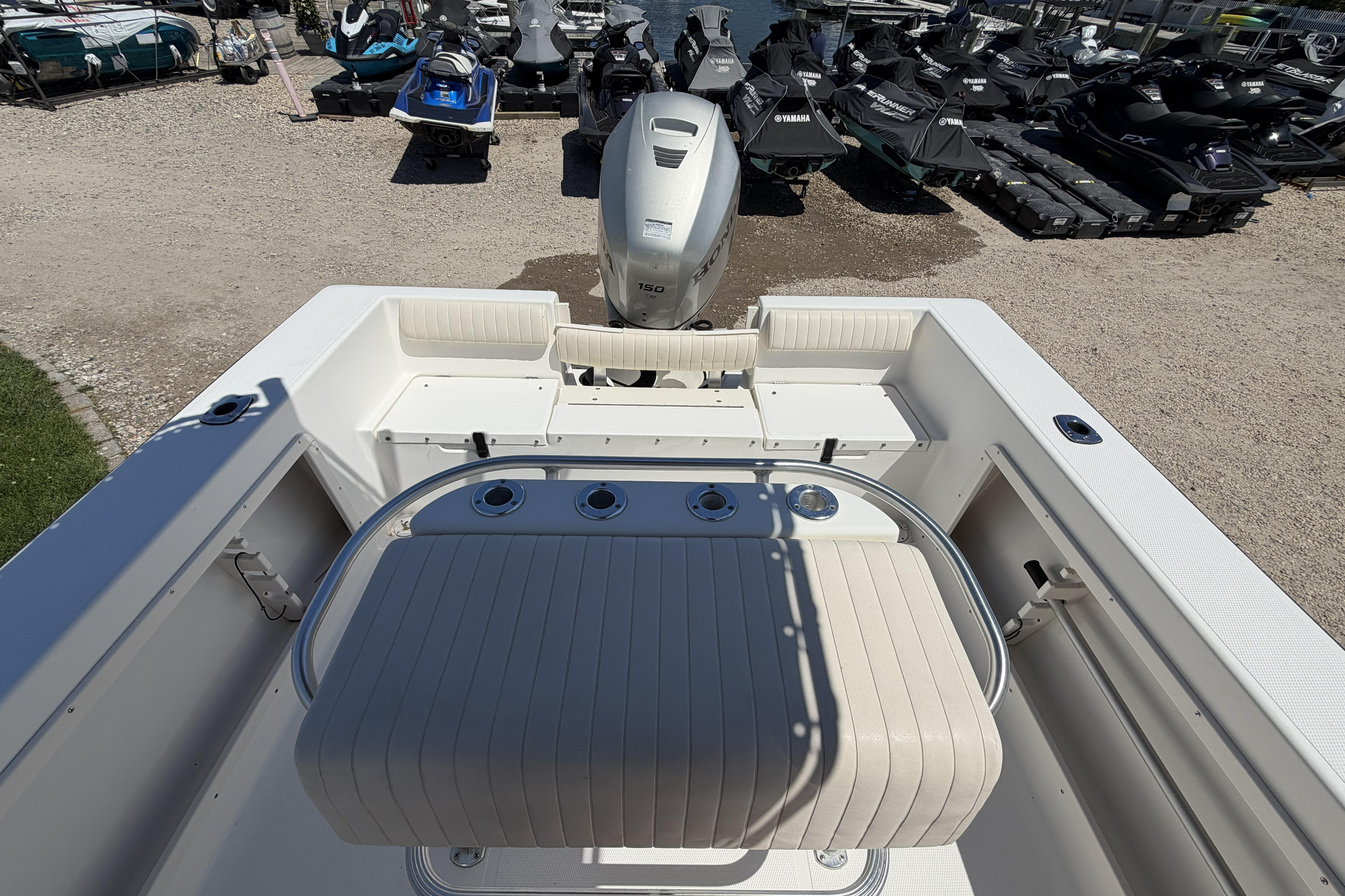 2006 Mako 212 Center Console boat interior with seating and motor, docked near jet skis.