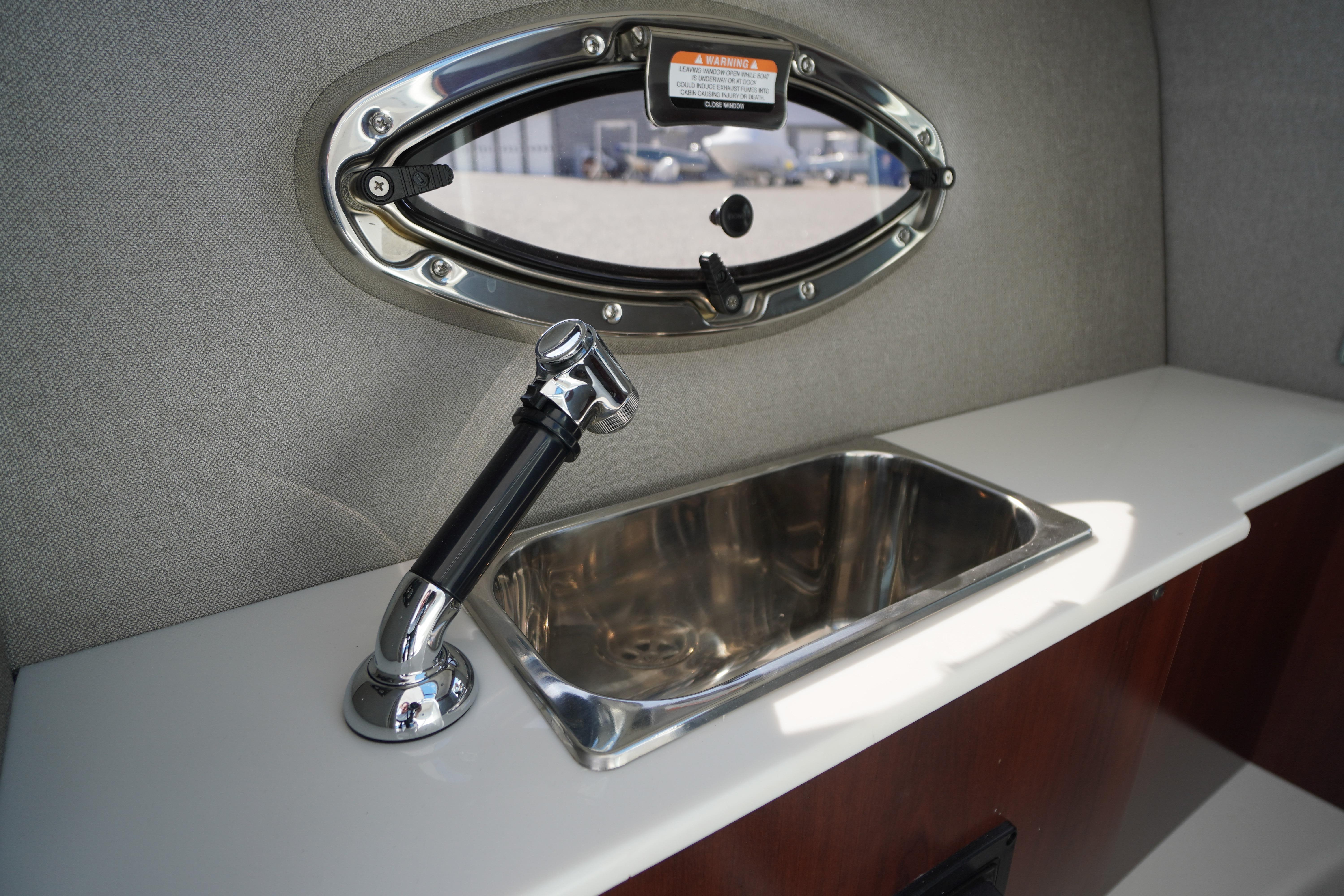 2026 Chaparral 270 OSX boat interior with sink and porthole window.