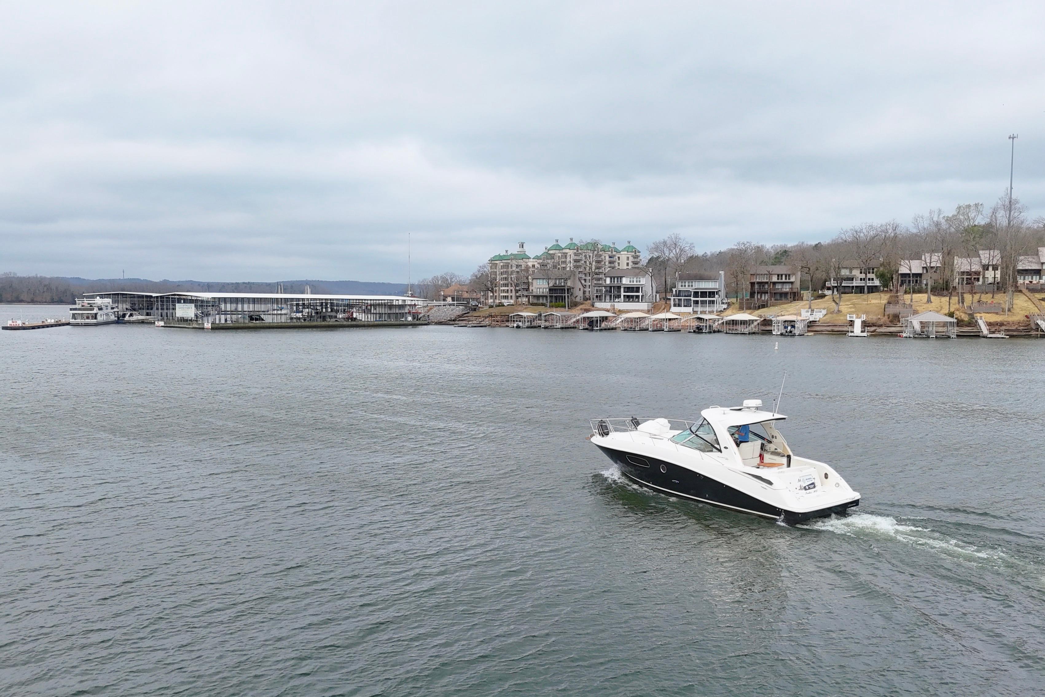 2009 Sea Ray Sundancer 350 cruising on a lake near waterfront homes and marina.