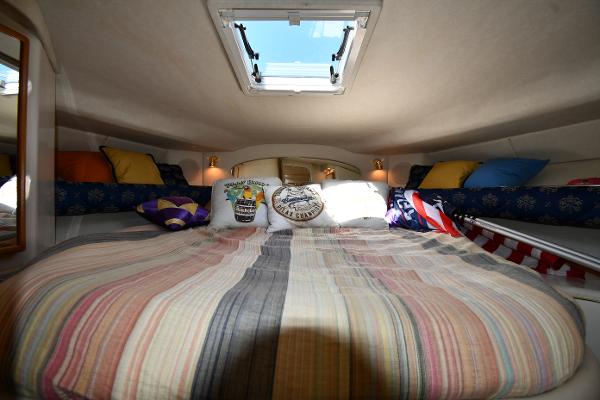 Cozy cabin interior of 1997 Sea Ray 400 Sundancer with skylight and colorful bedding.