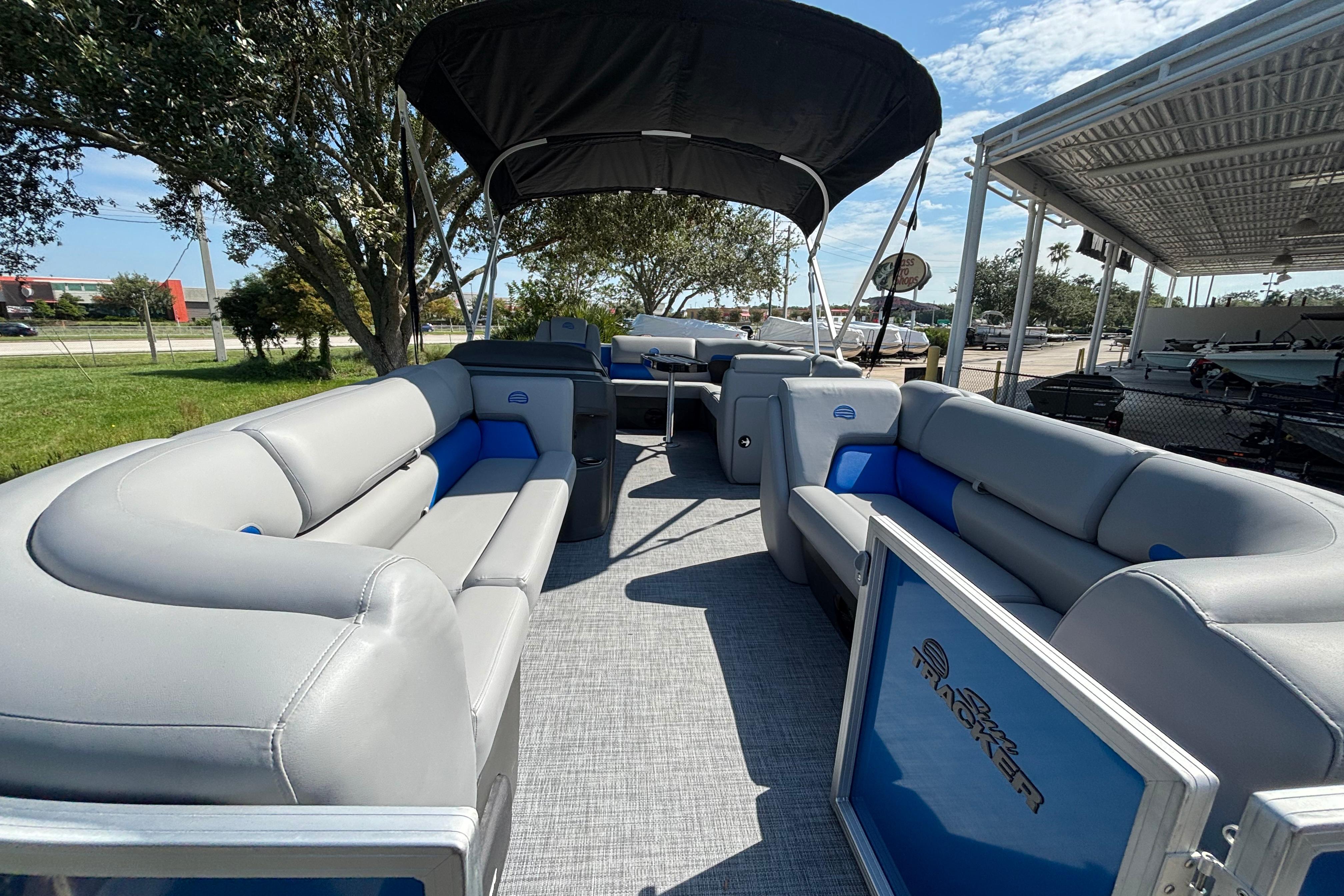 2026 Sun Tracker Party Barge 20 DLX with spacious seating and canopy, parked outdoors.