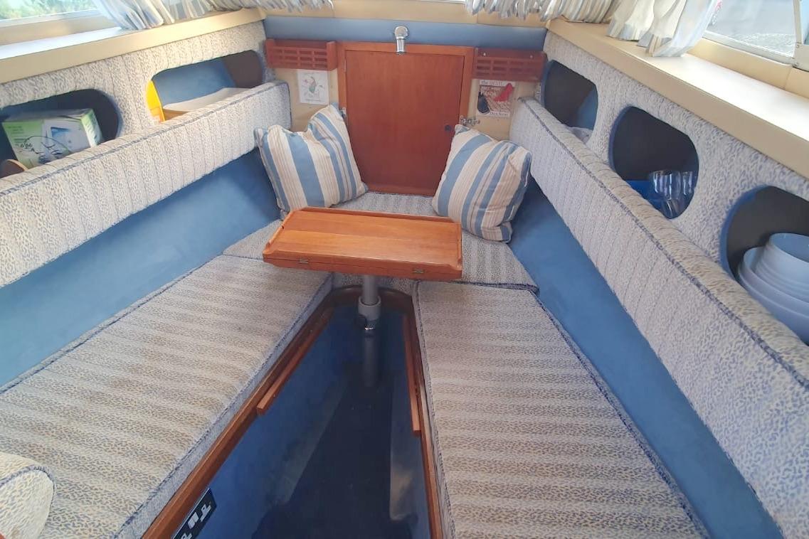 Cozy interior of 1989 Fairey Spearfish MKIII boat with striped cushions and wooden table.
