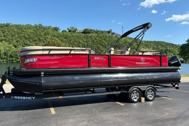 2025 Regency 250 DL3 pontoon boat on trailer, parked near a scenic lake.