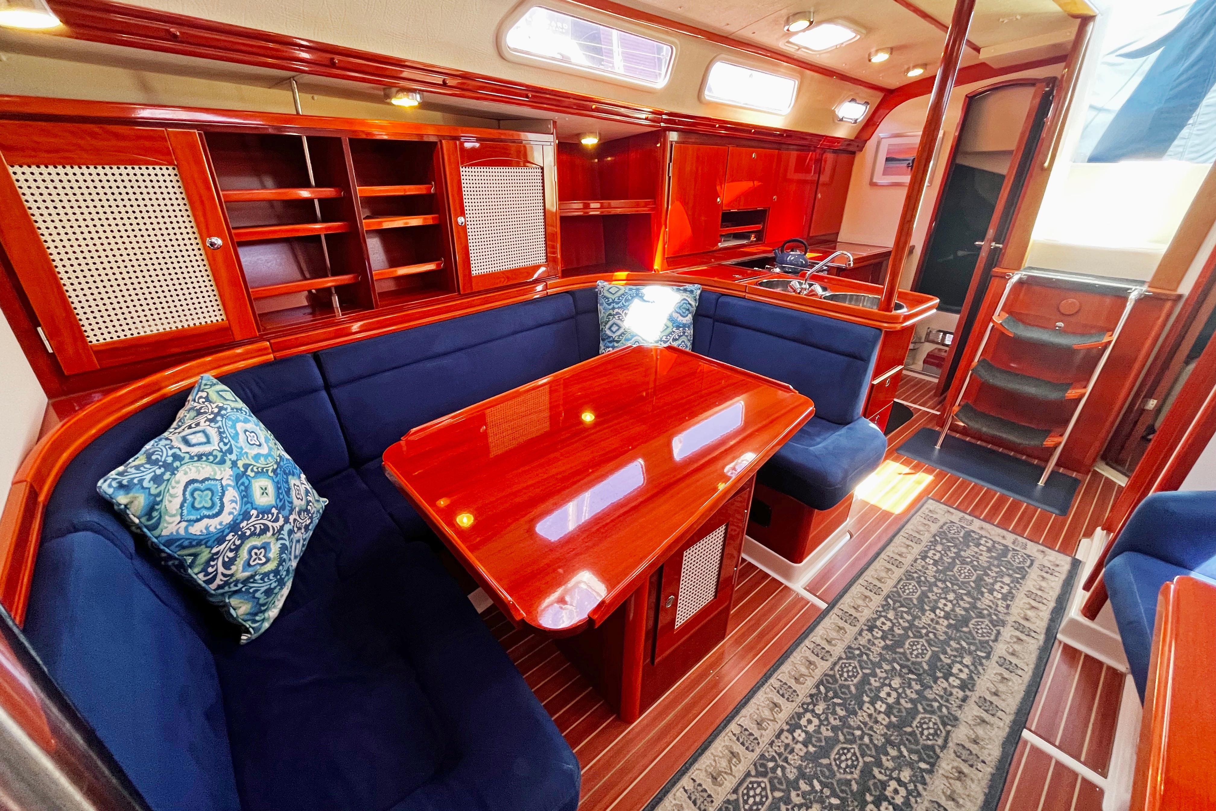 Luxurious 2004 Hanse 411 yacht interior with polished wood, blue seating, and elegant decor.