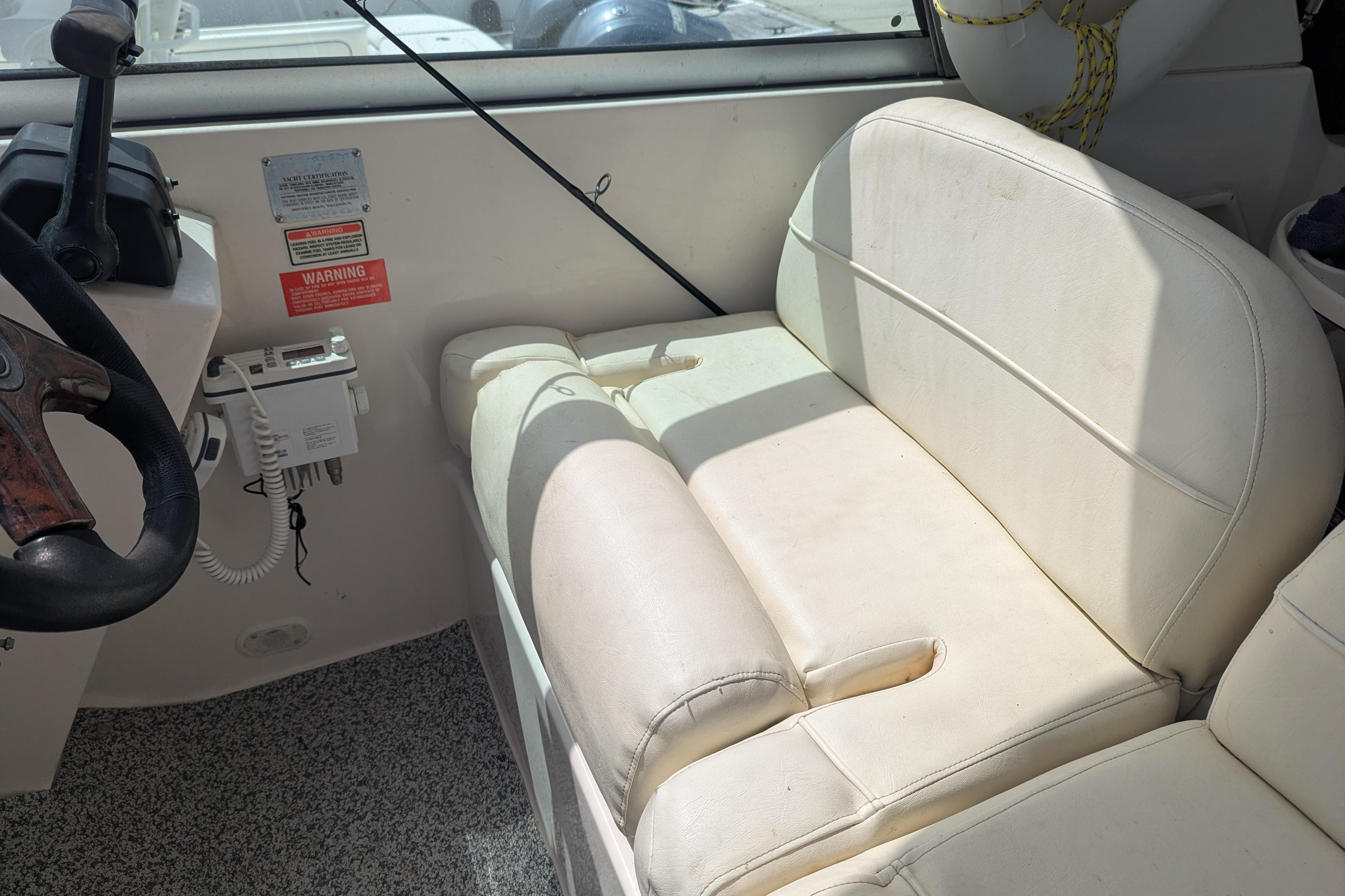 Interior of a 2003 Monterey 282 Cruiser boat with white seating and steering controls.