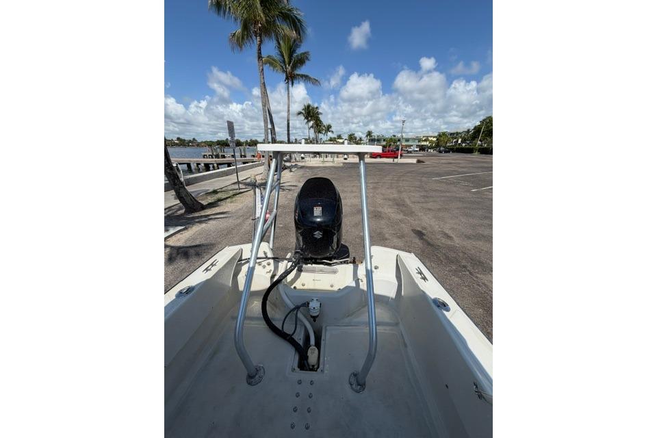 1990 Boston Whaler 17 Newport boat with outboard motor, parked near waterfront under palm trees.